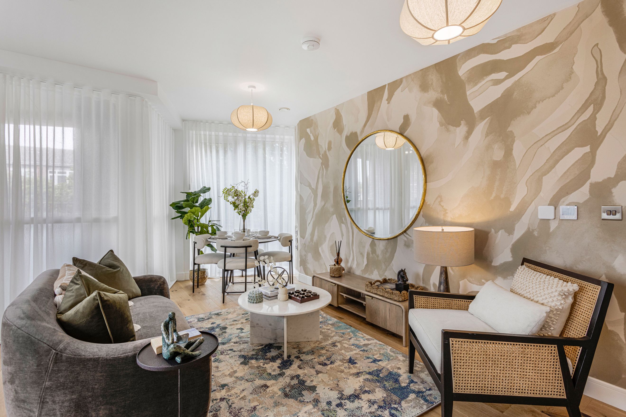 A living and dining area with a sofa, coffee table, dining table, chairs, and a patterned wallpaper.