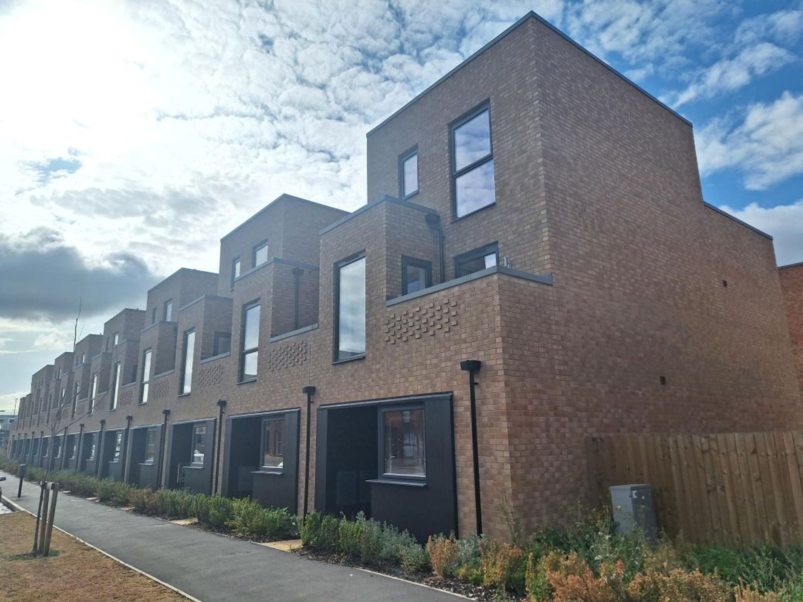 A row of modern brick townhouses with large windows and dark entrances.