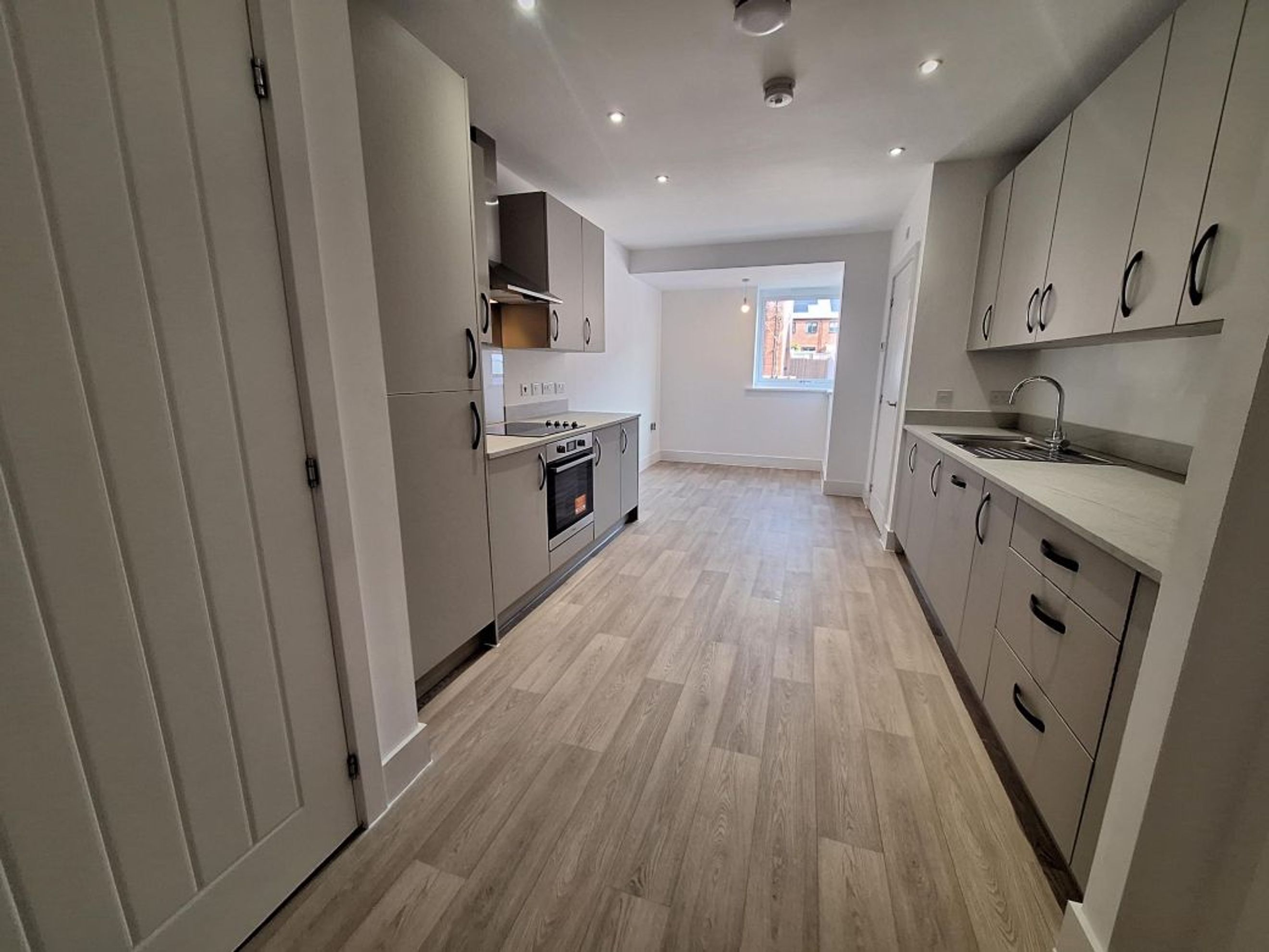 A modern kitchen with grey cabinets, a built-in oven, and a sink.
