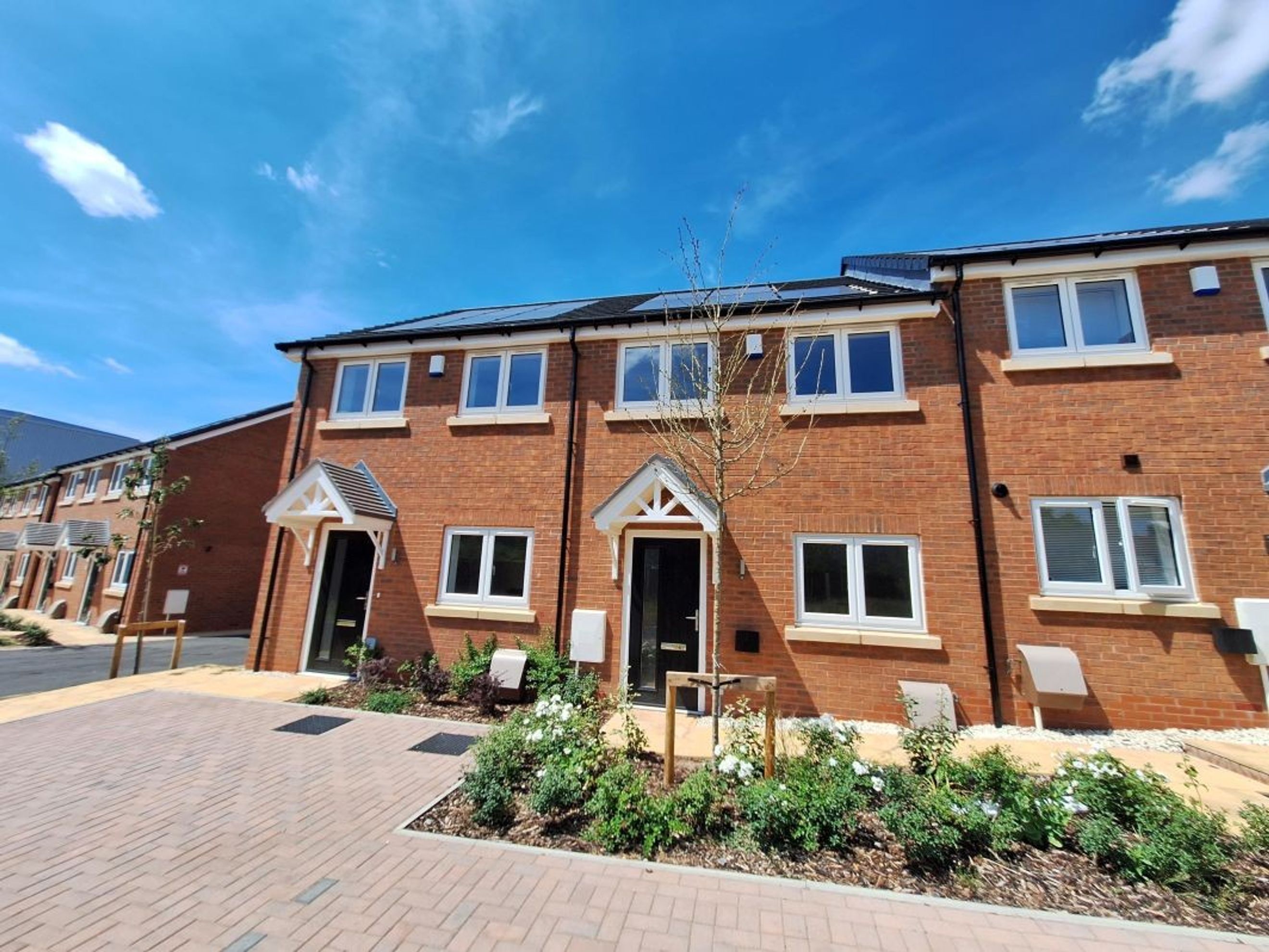 A row of new brick townhouses with white-framed windows and solar panels on the roof.