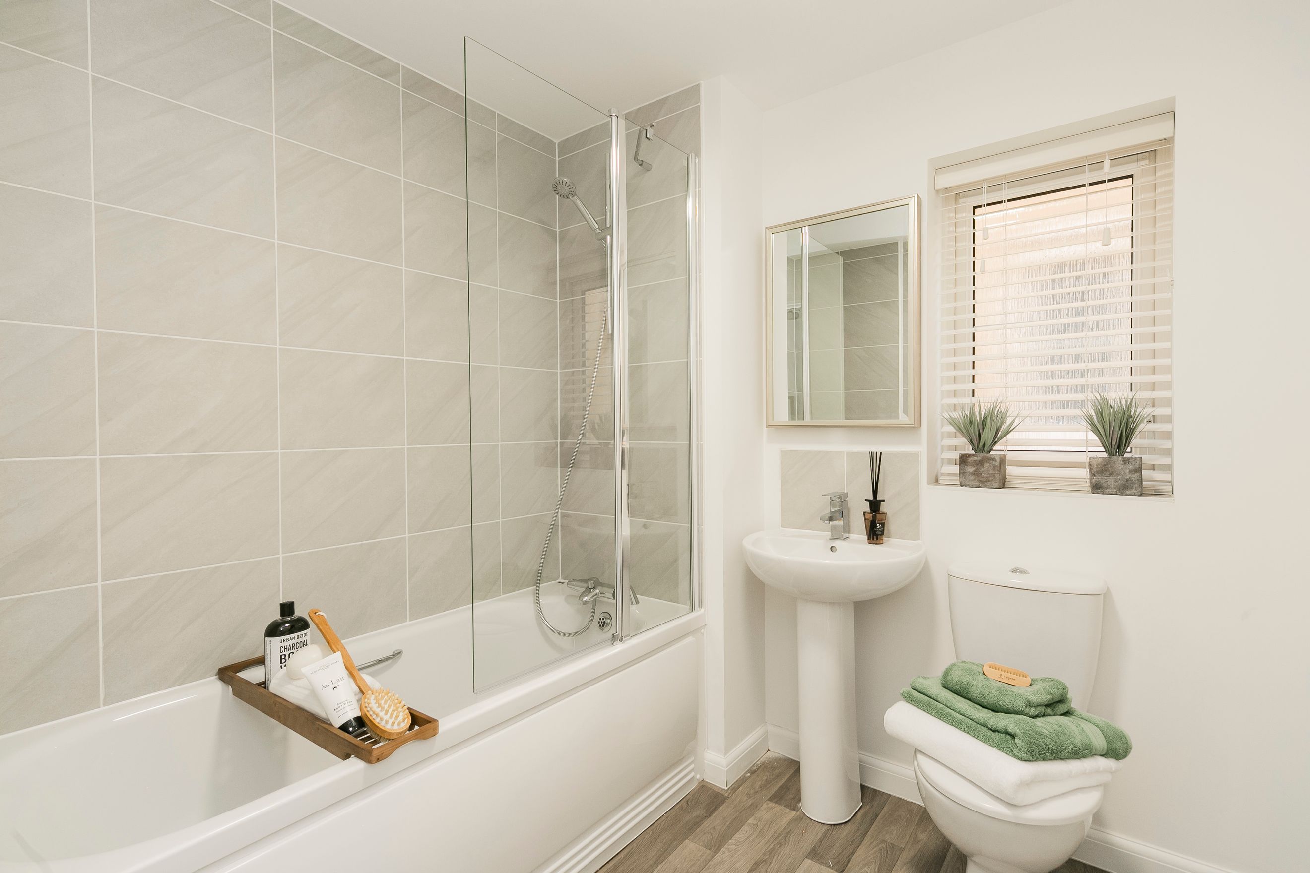 A bathroom with a bathtub, shower screen, sink, toilet, and mirror.