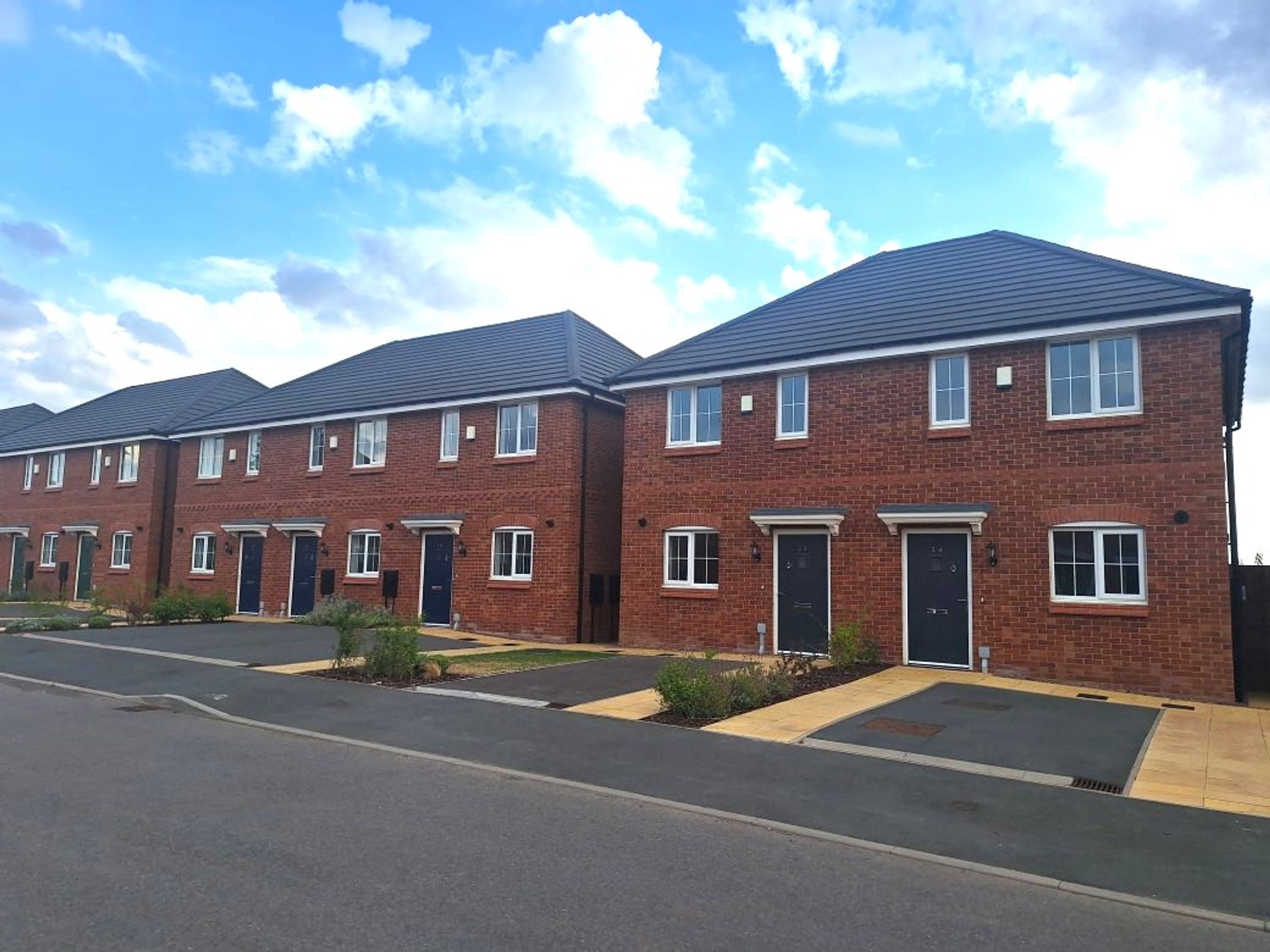 A row of new brick townhouses with dark roofs and white windows.