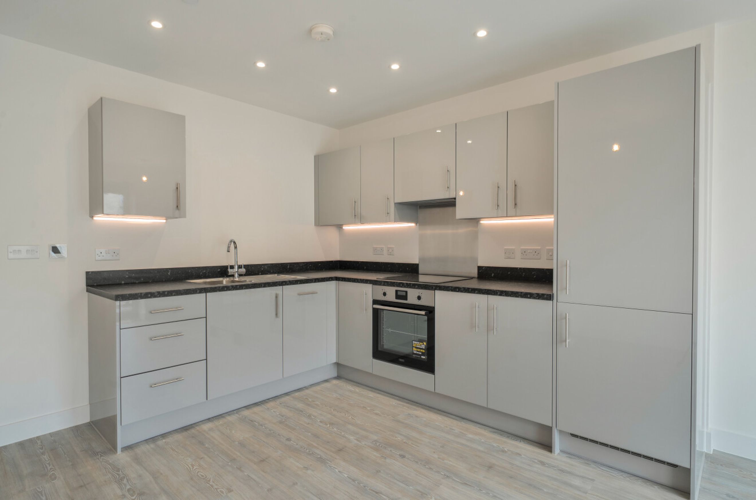A modern kitchen with grey cabinets, dark countertops, and integrated appliances.