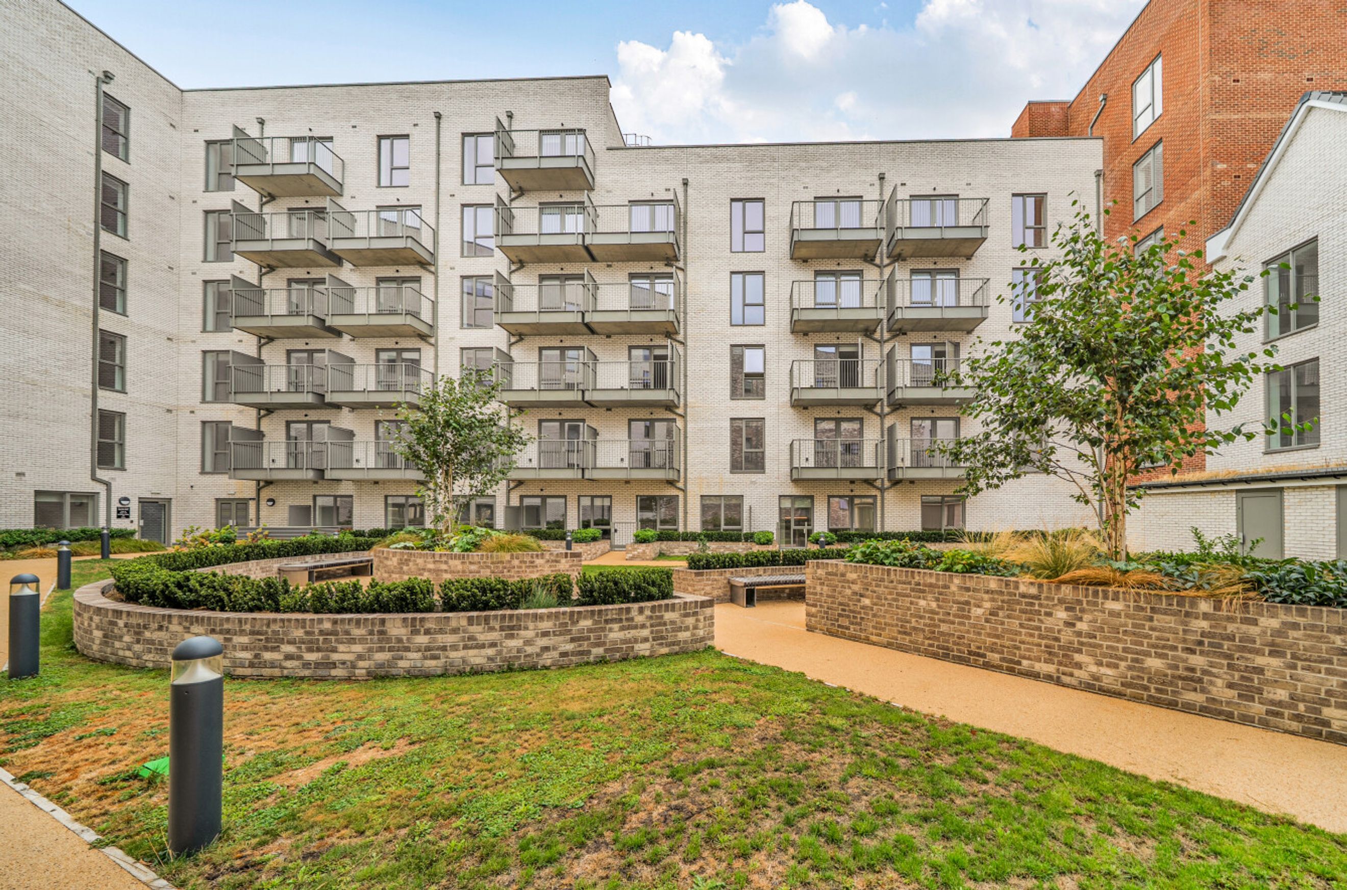 A courtyard with modern apartment buildings and landscaped gardens.