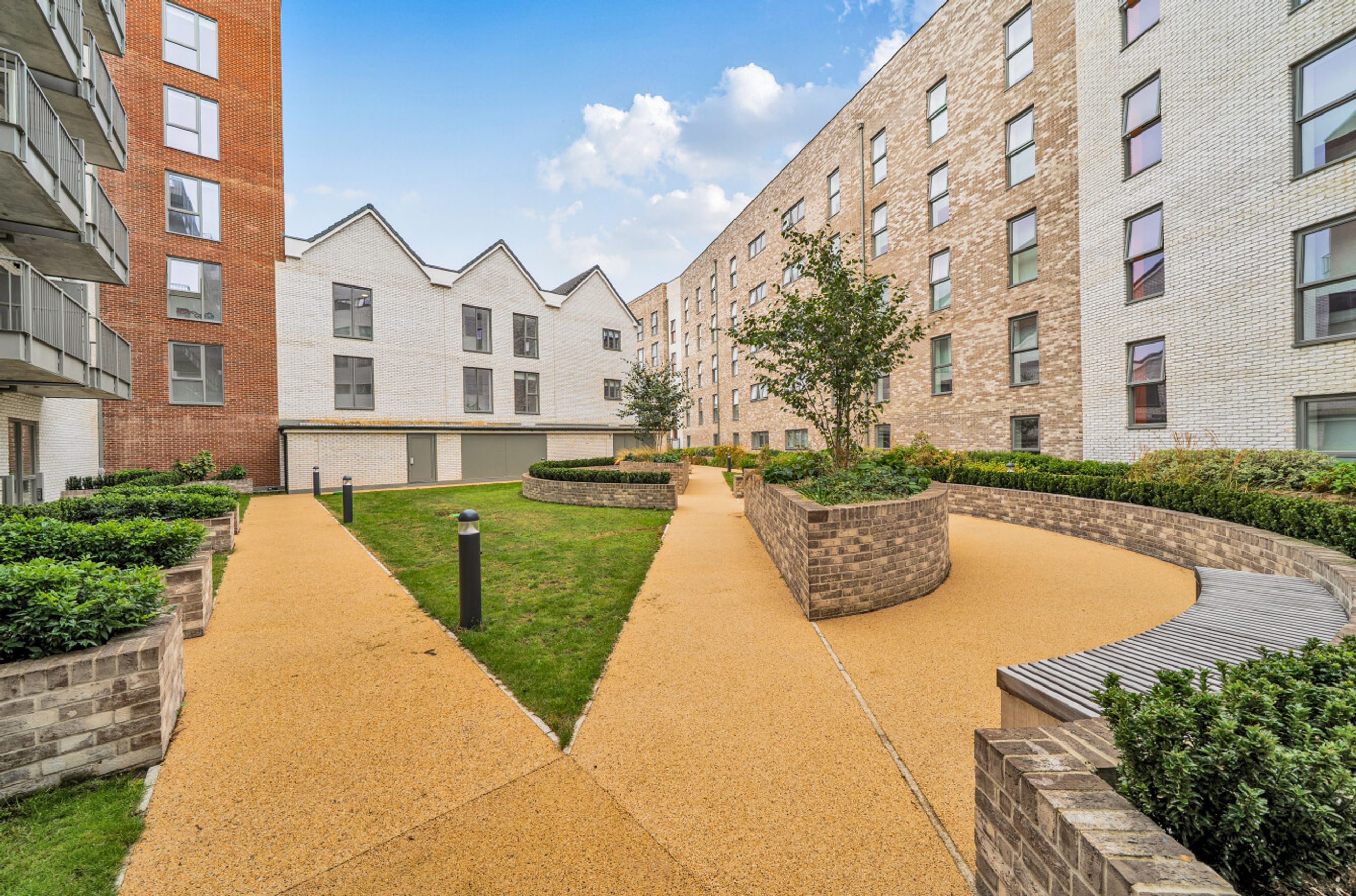 A courtyard with pathways, grass, trees, and buildings.