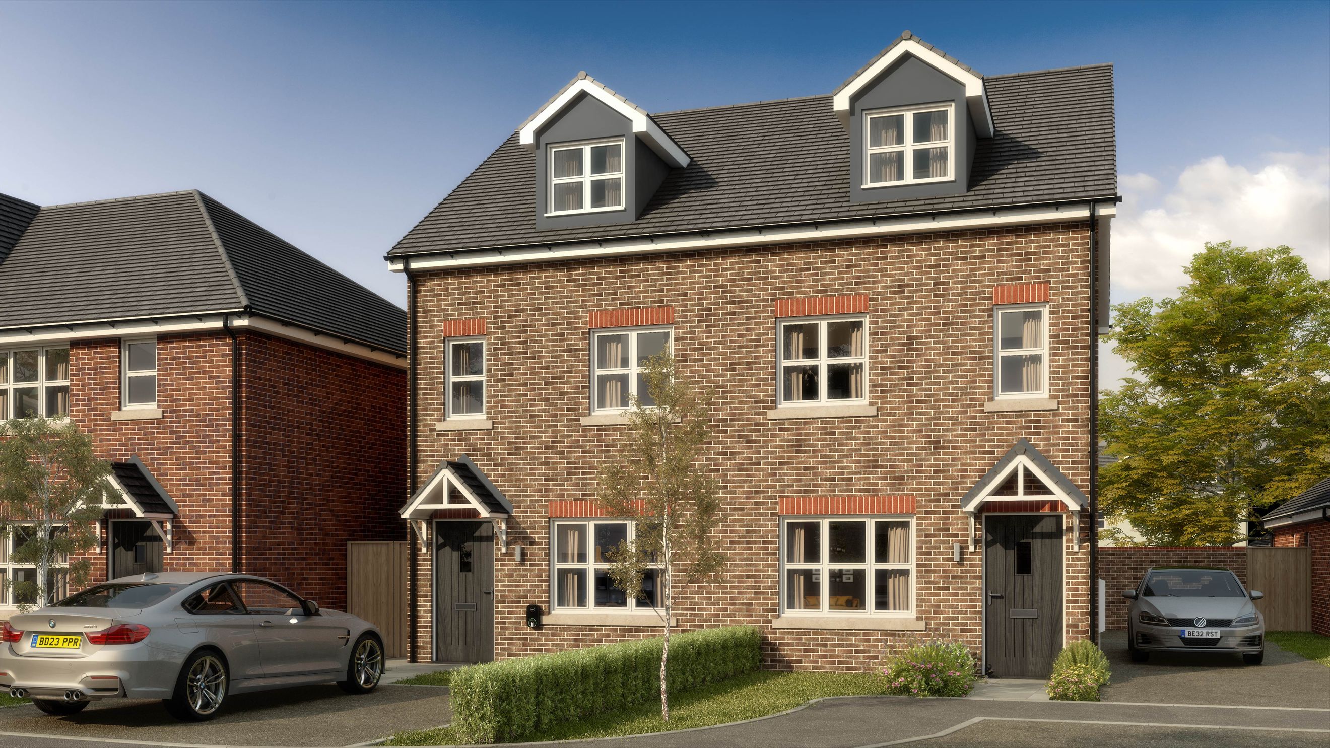 A pair of new brick houses with dormer windows and parked cars in front.