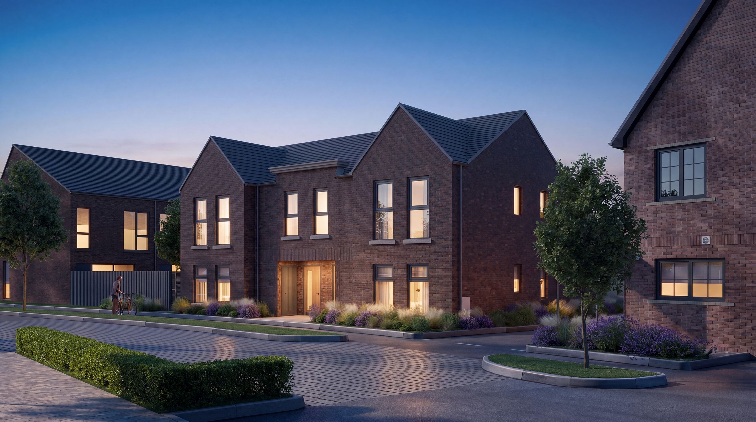 A row of modern brick houses with illuminated windows at dusk.