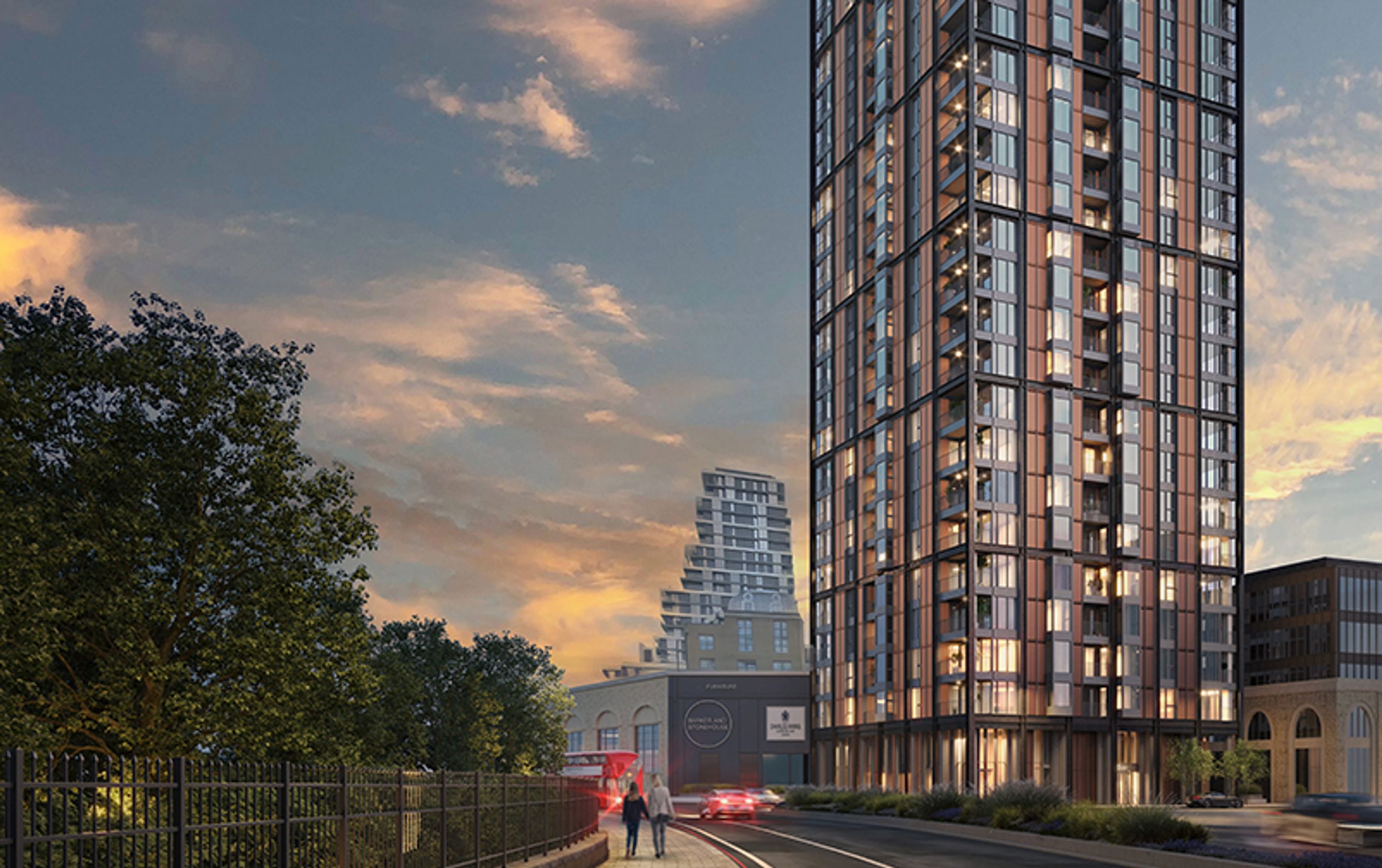 A tall, modern apartment building with many windows and balconies, set against a sunset sky with clouds.