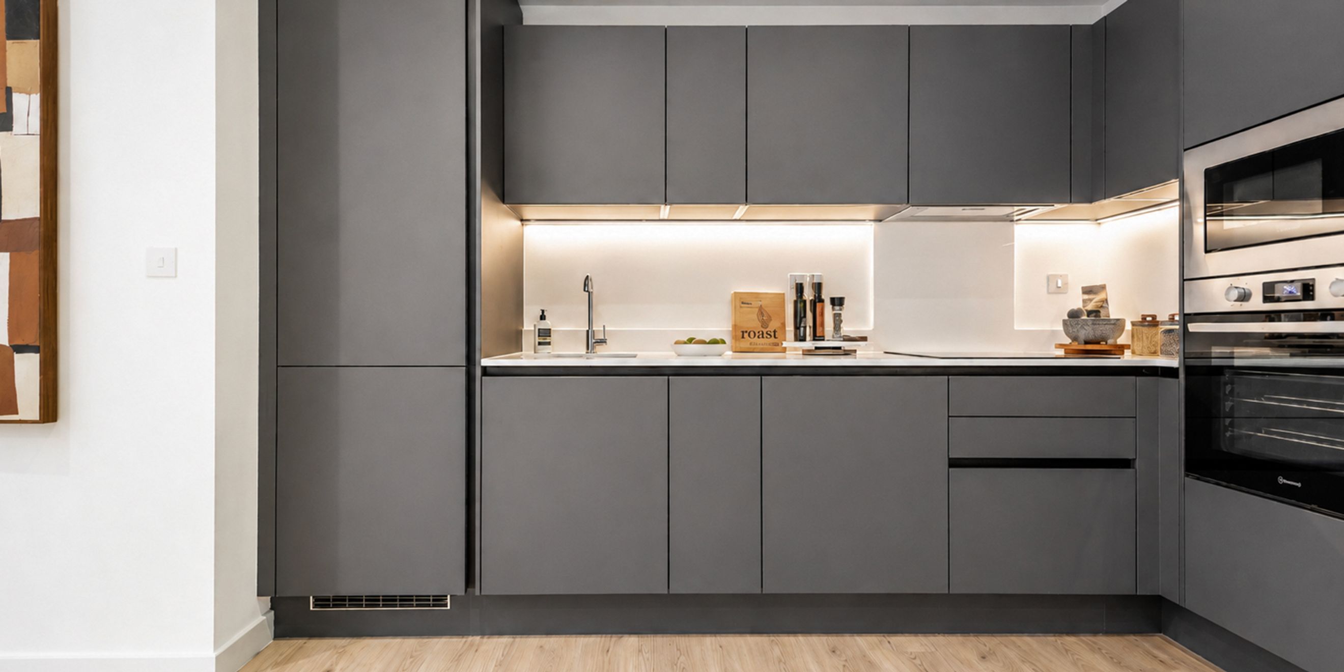 A modern kitchen with dark grey cabinets, a sink, and integrated appliances.