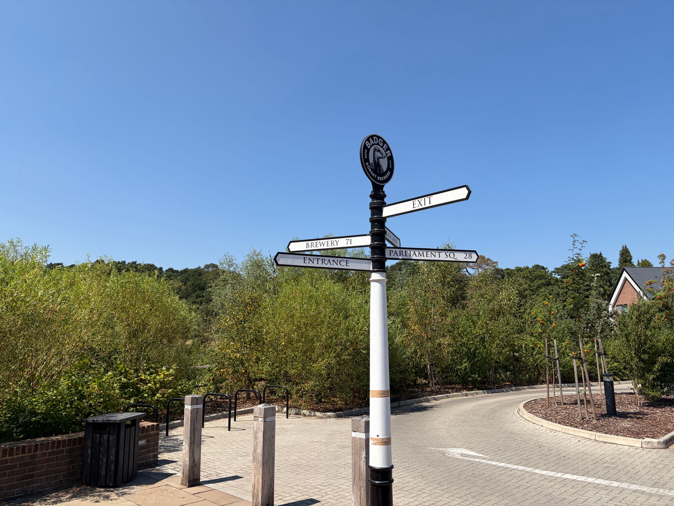 A signpost with directions to the brewery, entrance, and Parliament Square, with the Badger Brewery logo at the top.