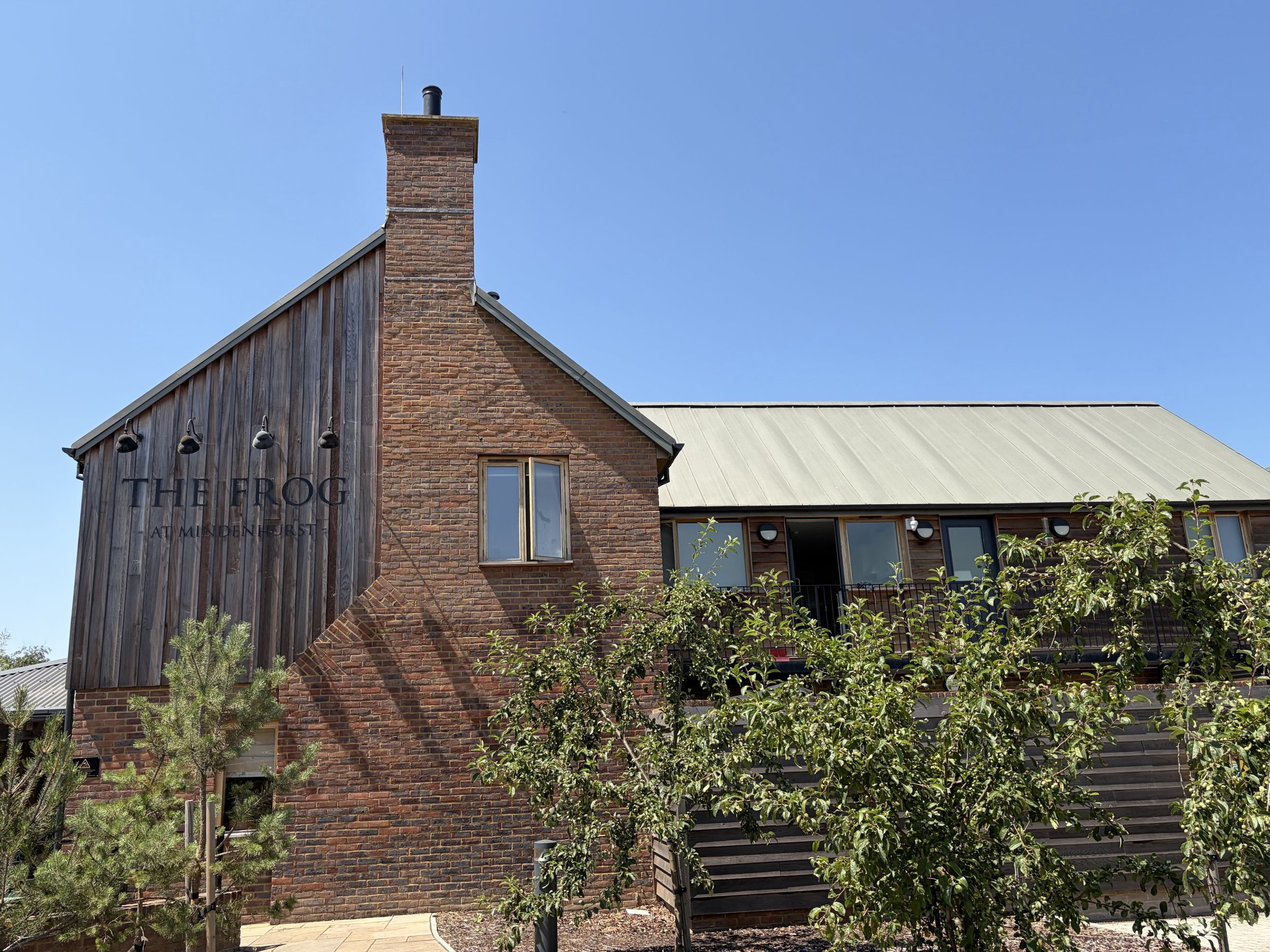 A building with a brick chimney, wooden siding, and a metal roof.