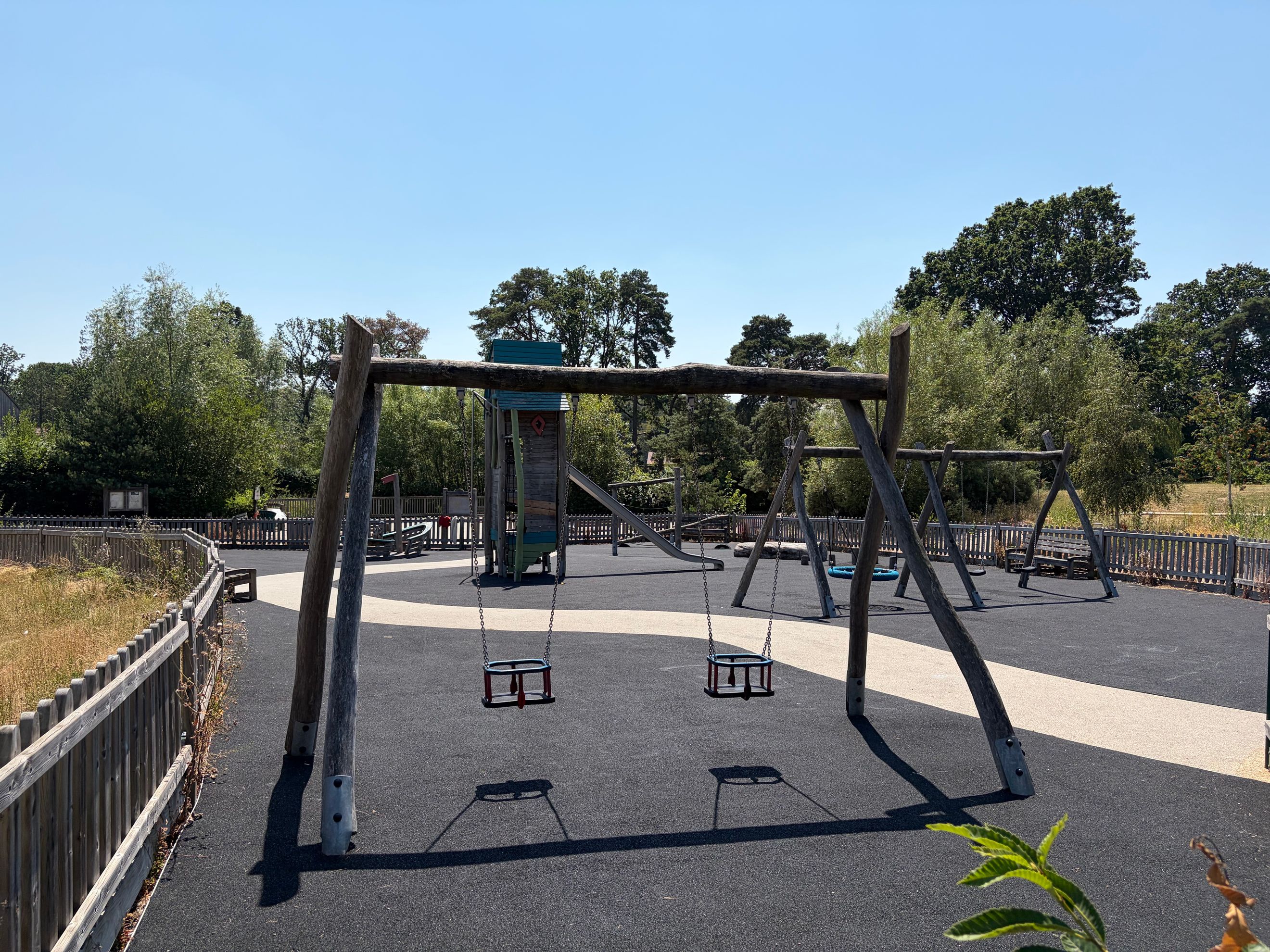 A playground with swings, a play structure, and a slide.