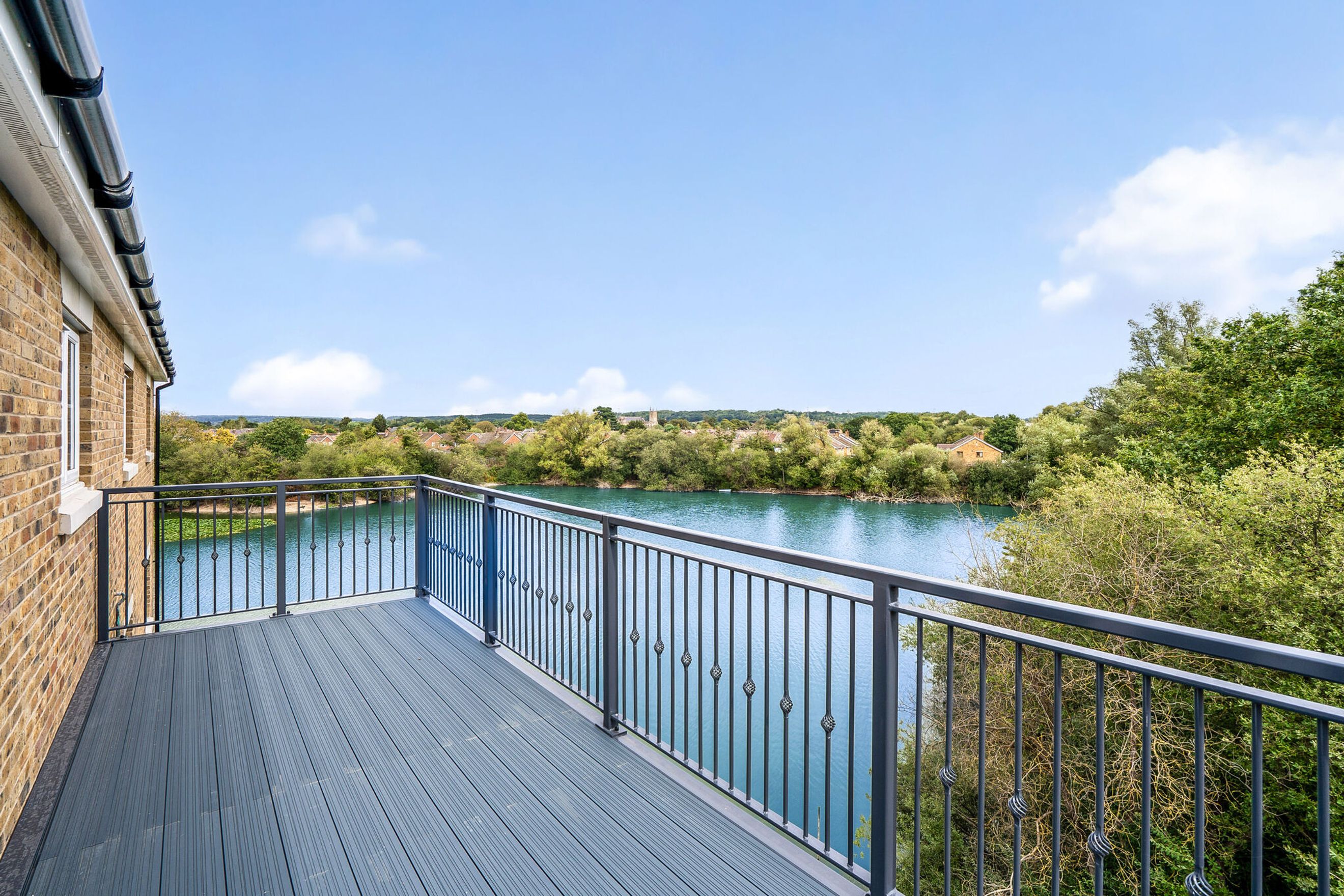 A balcony with a view of a lake and trees.