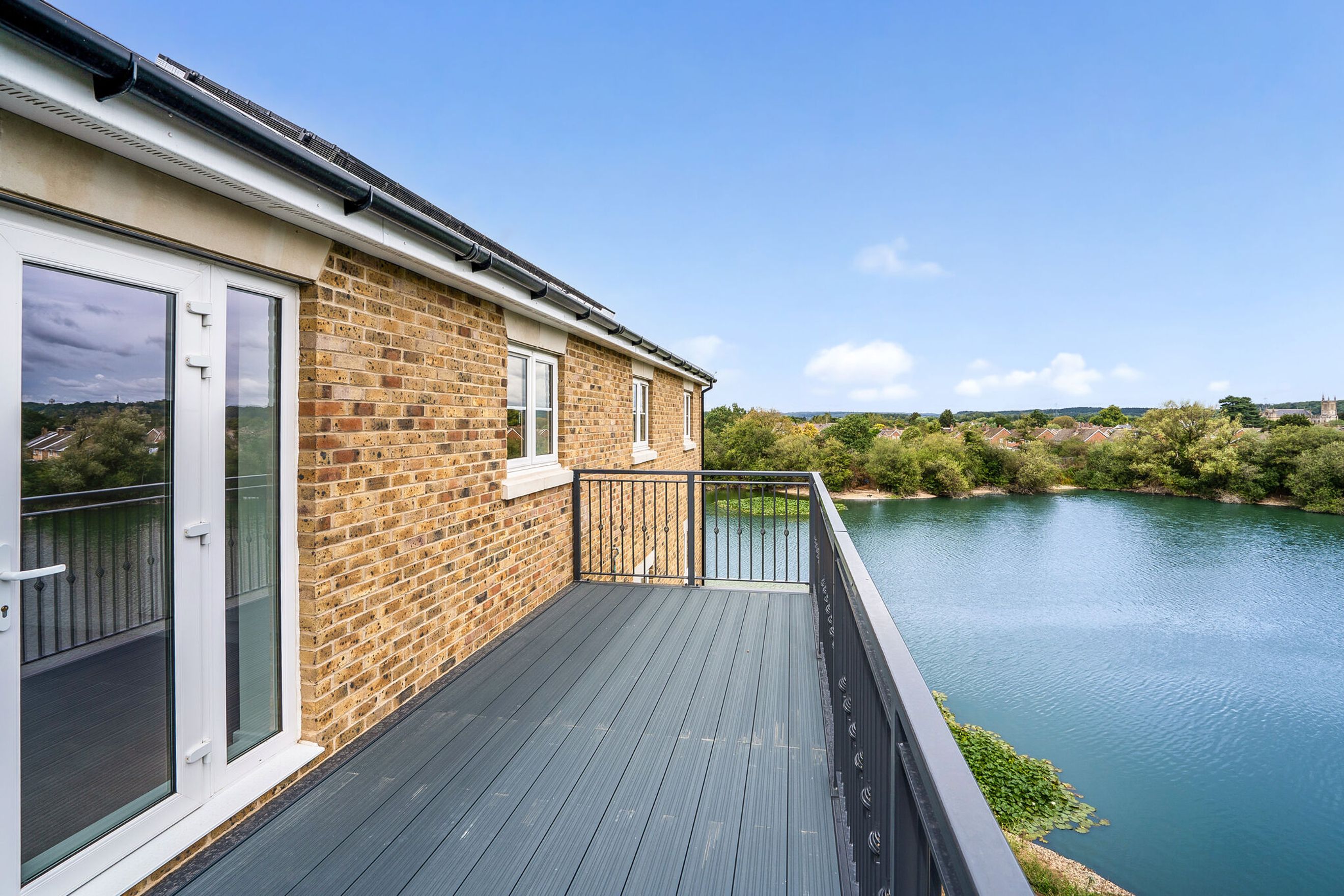 A balcony overlooking a lake with a brick building on the left.