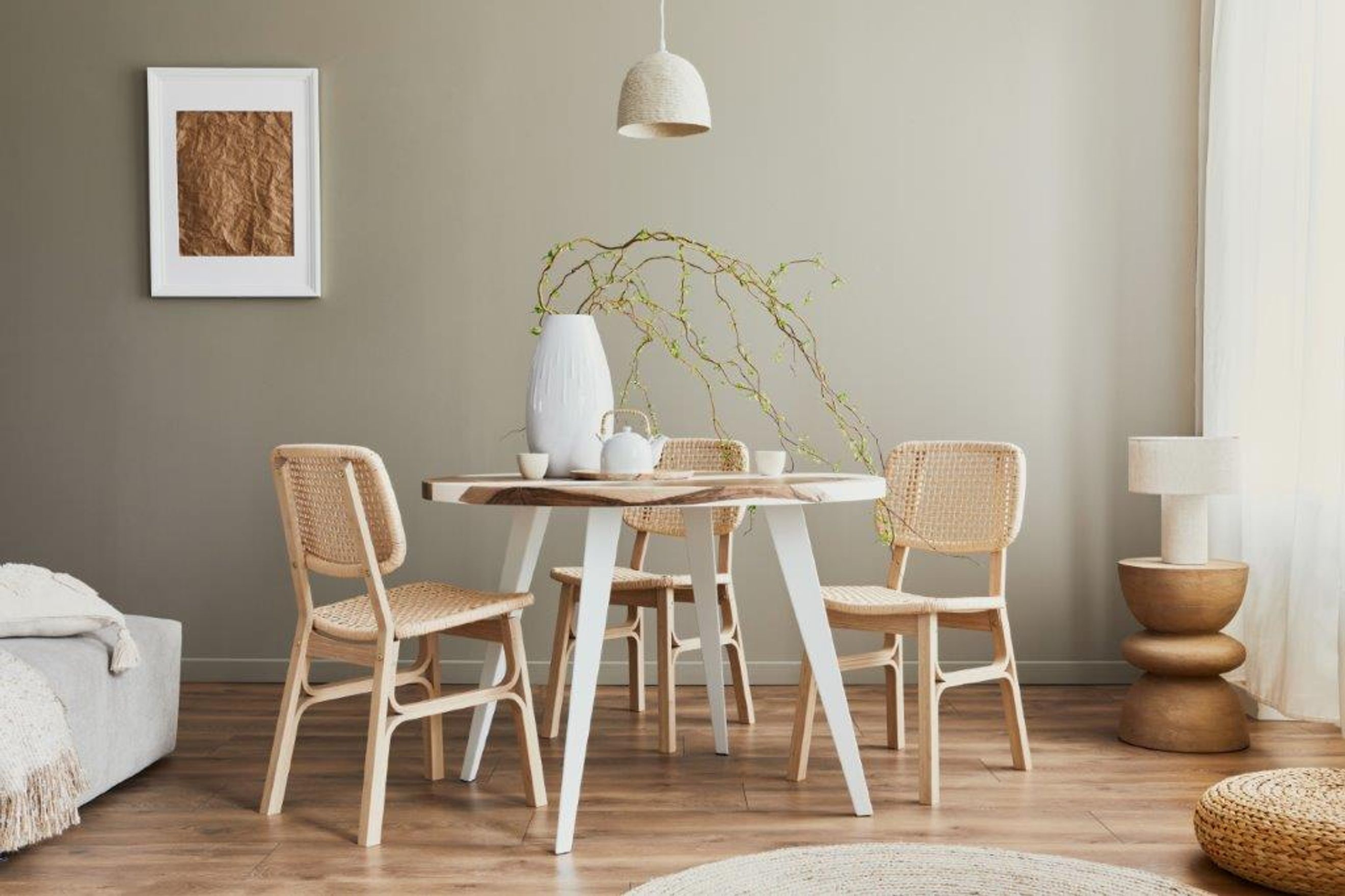A dining table with four chairs, a vase, and a teapot.