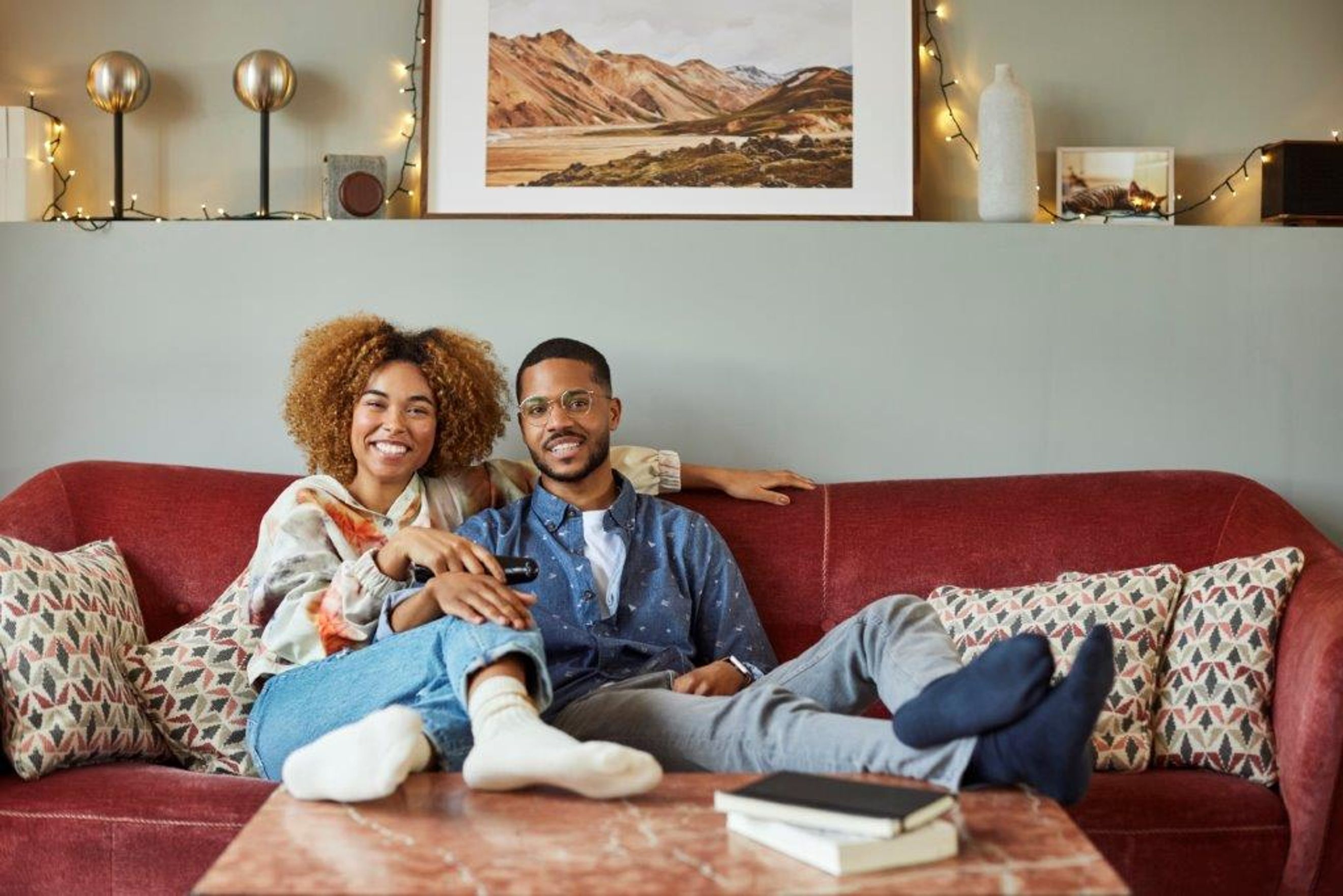 A couple sitting on a red couch in a living room.