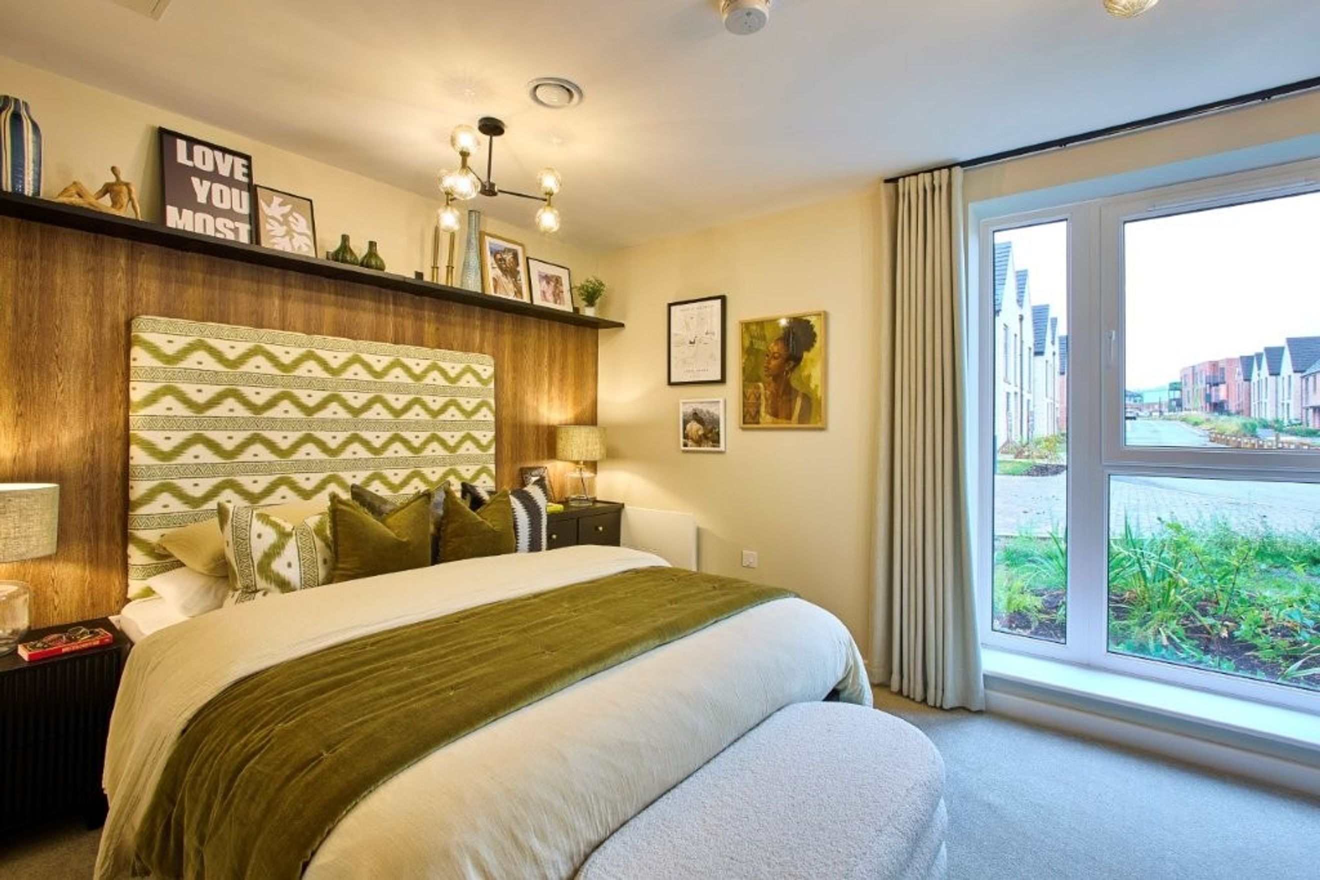 A bedroom with a bed, headboard, nightstand, and a large window.