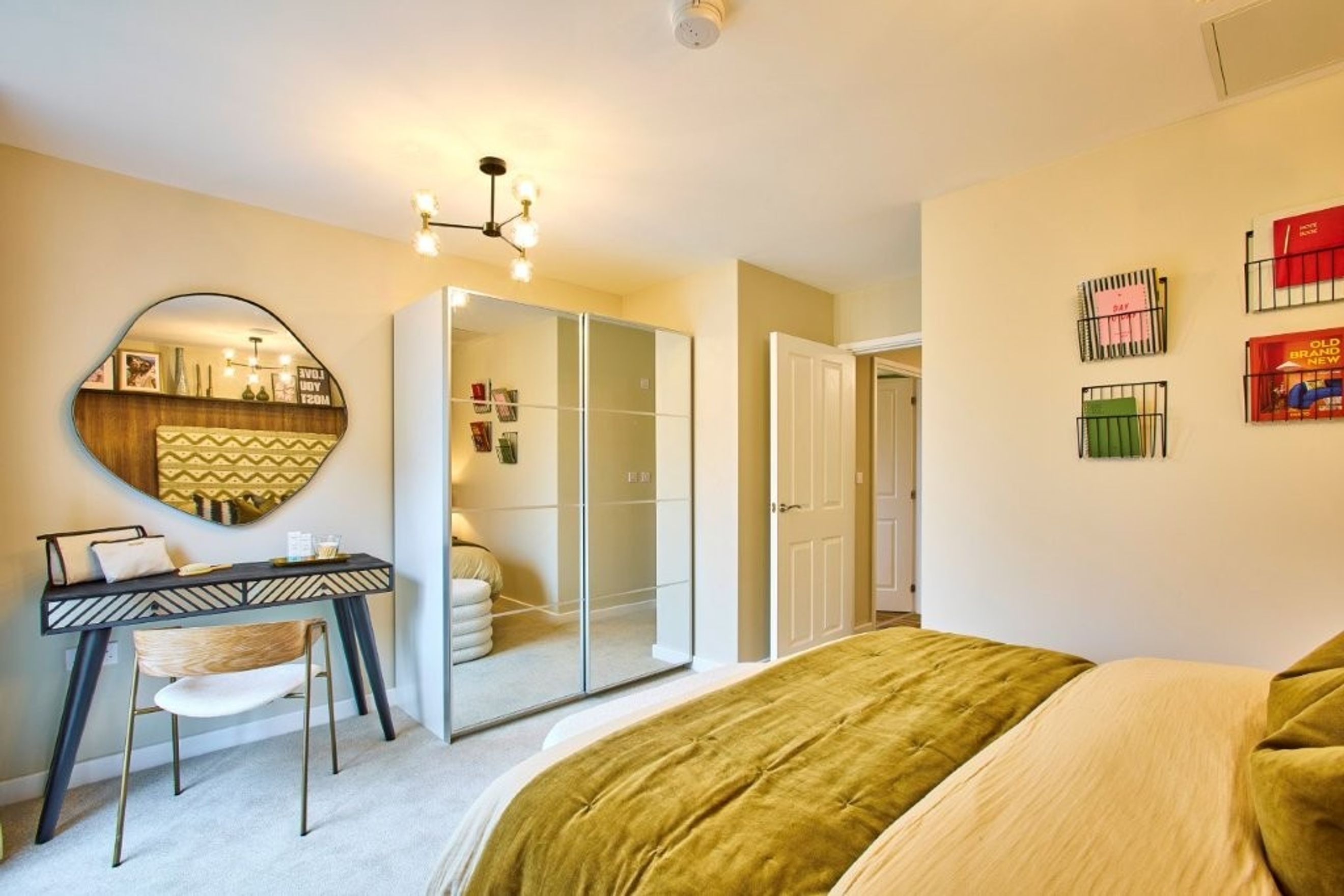 A bedroom with a bed, a dressing table, a mirror, and a wardrobe.