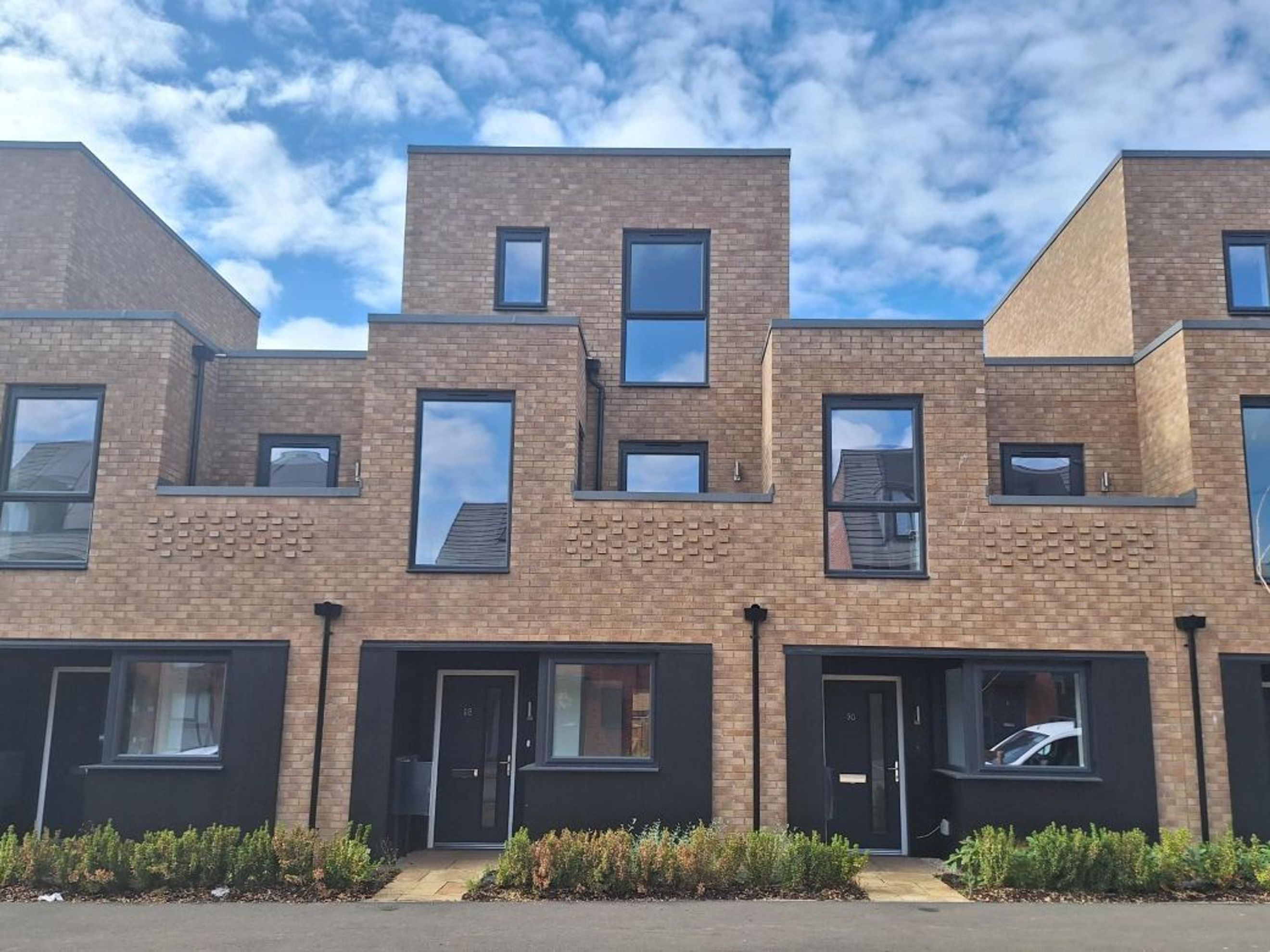 A row of modern brick townhouses with dark window frames and entrances.