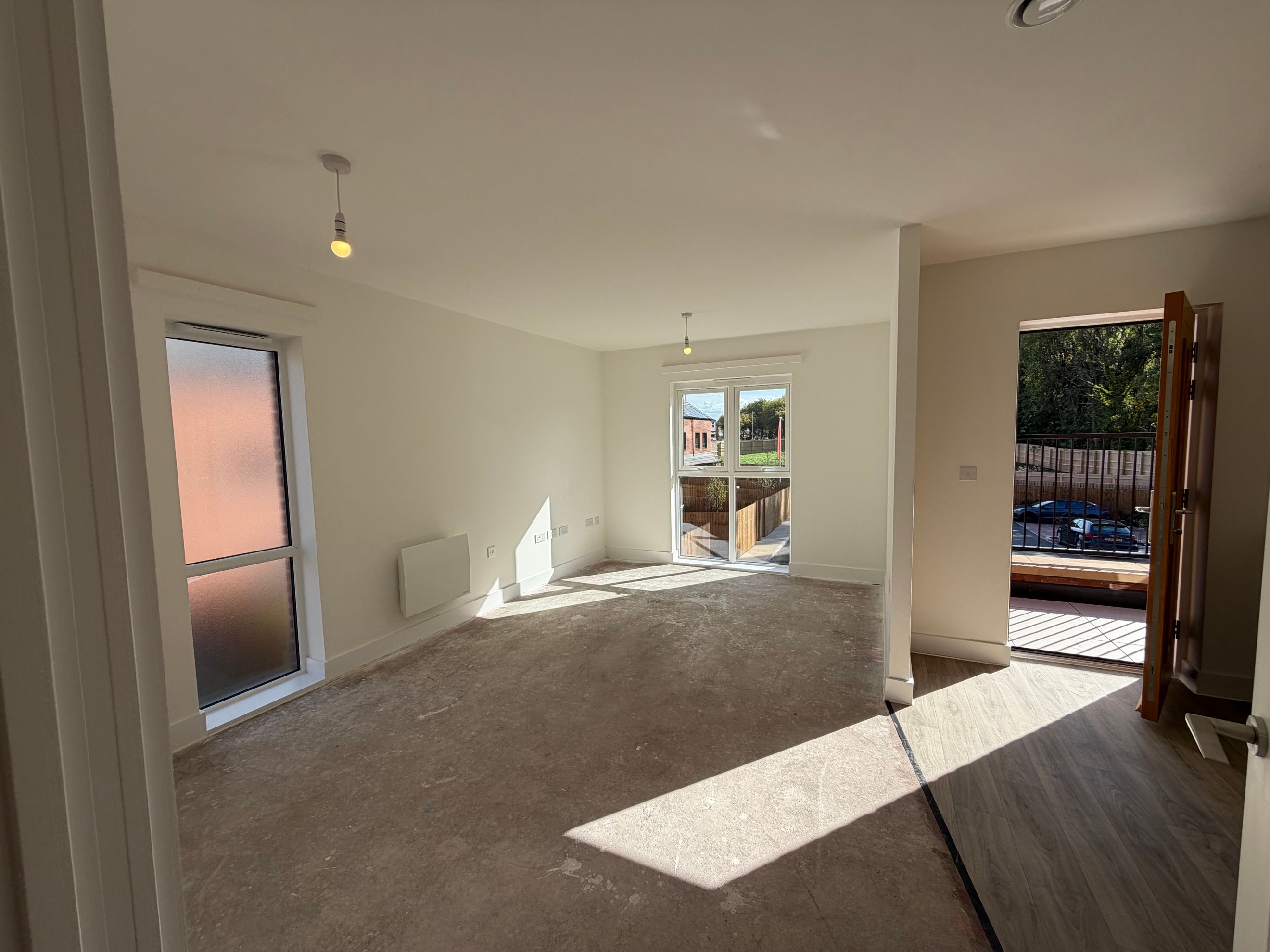 A living room with windows, a heater, and an open doorway leading outside.