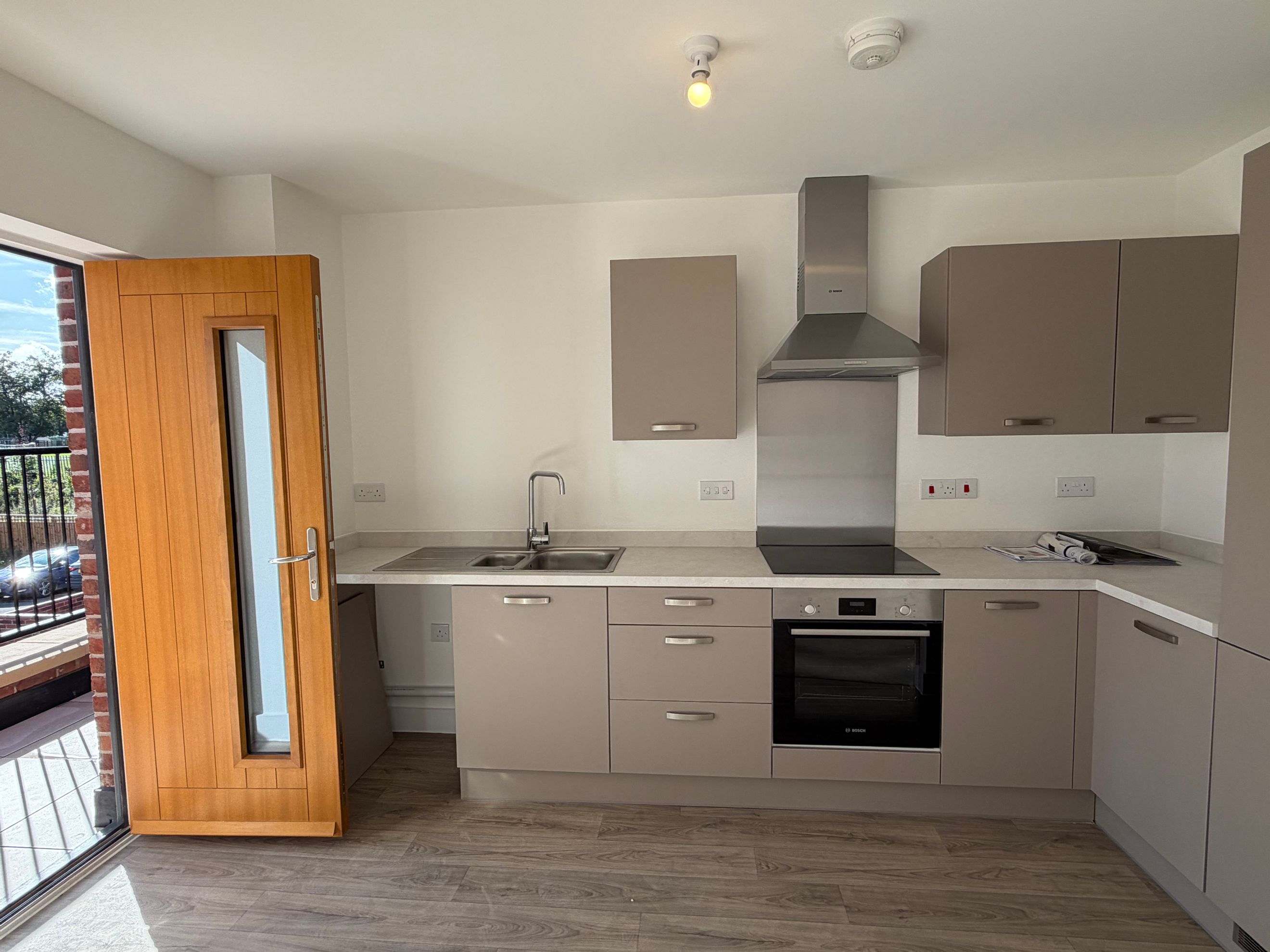 A modern kitchen with taupe cabinets, a stainless steel oven, and a double sink.