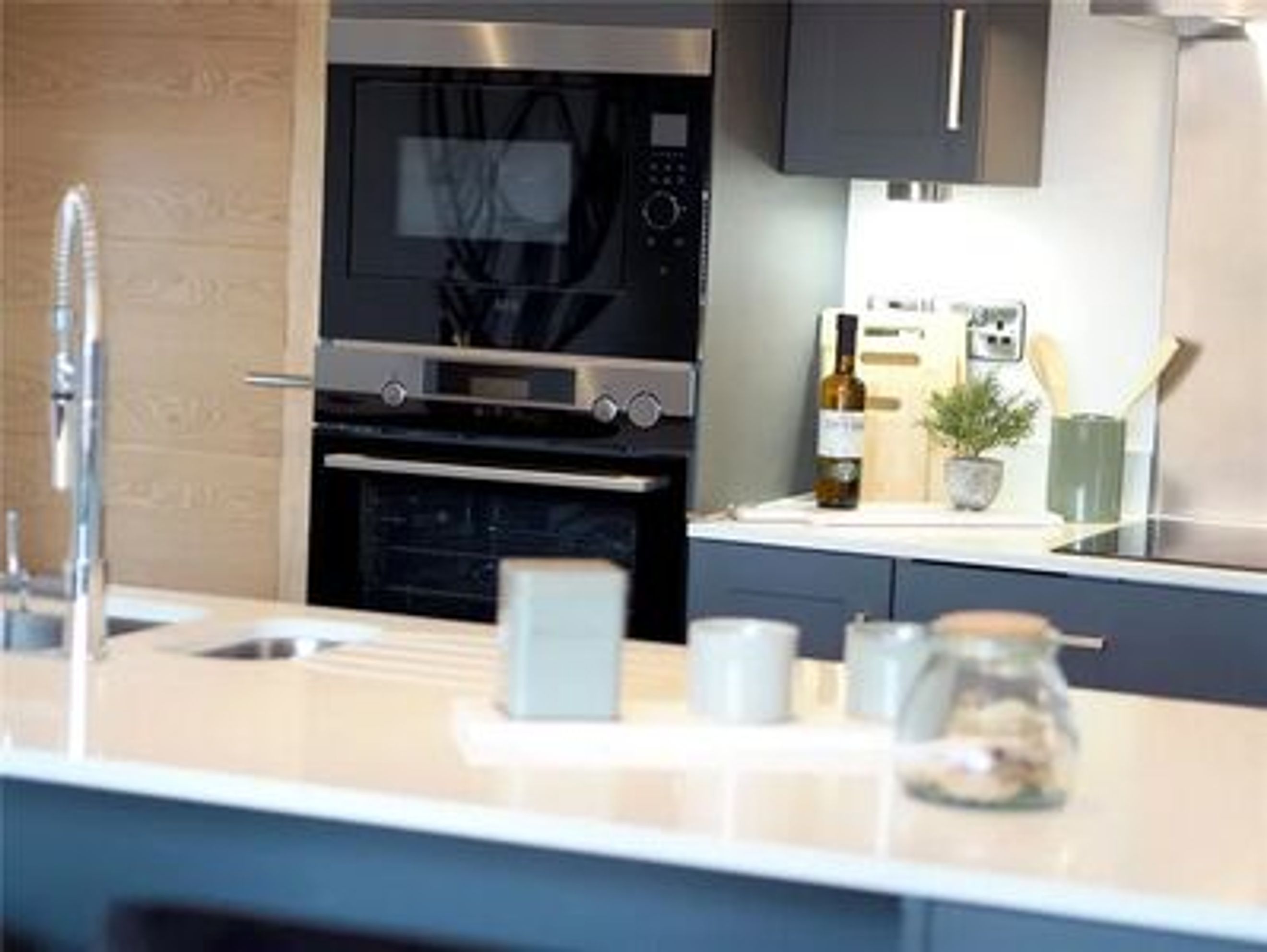 A kitchen counter with a sink, faucet, oven, microwave, and decorative items.