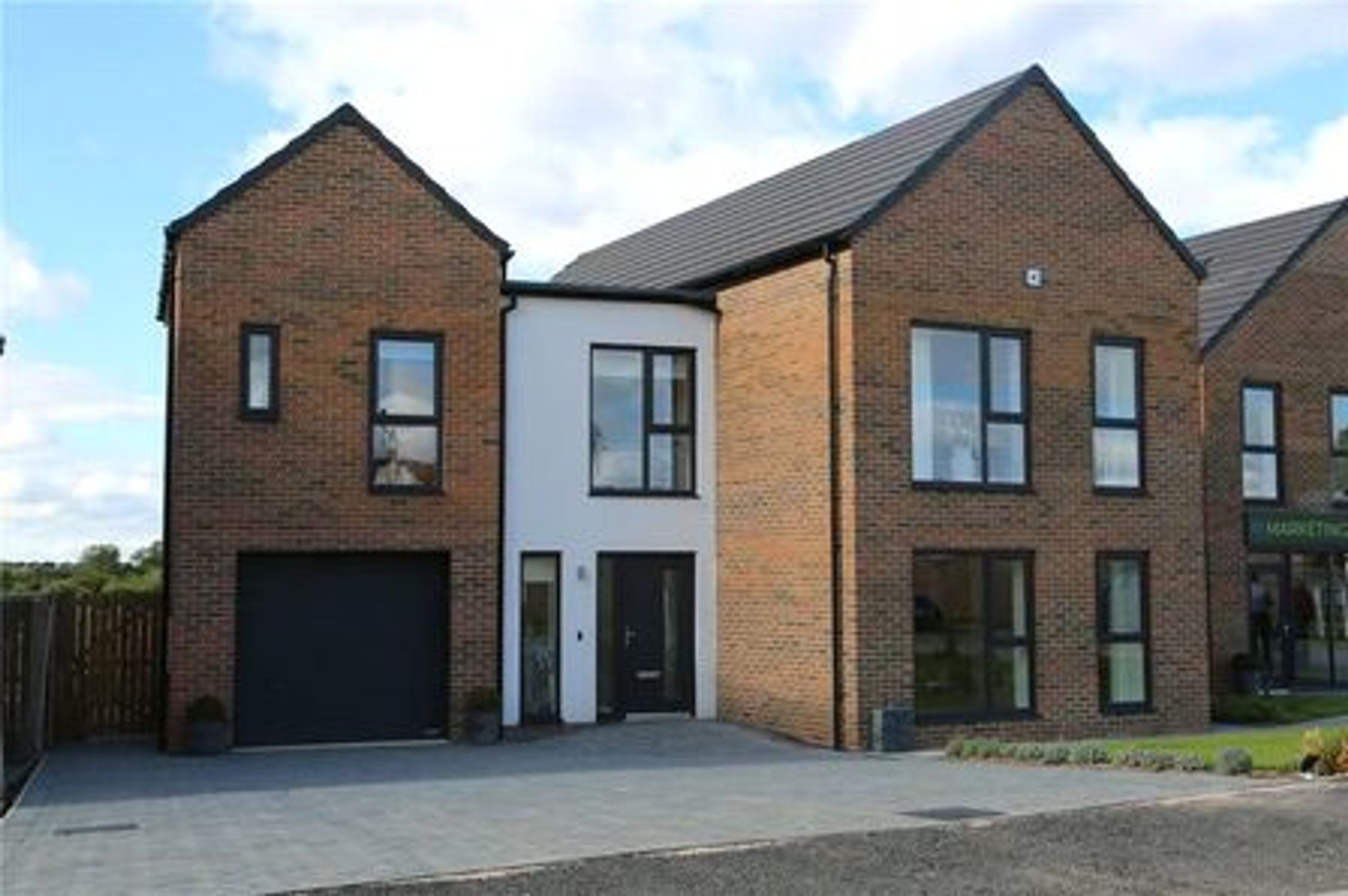 A modern house with brick and white render, featuring a garage and multiple windows.