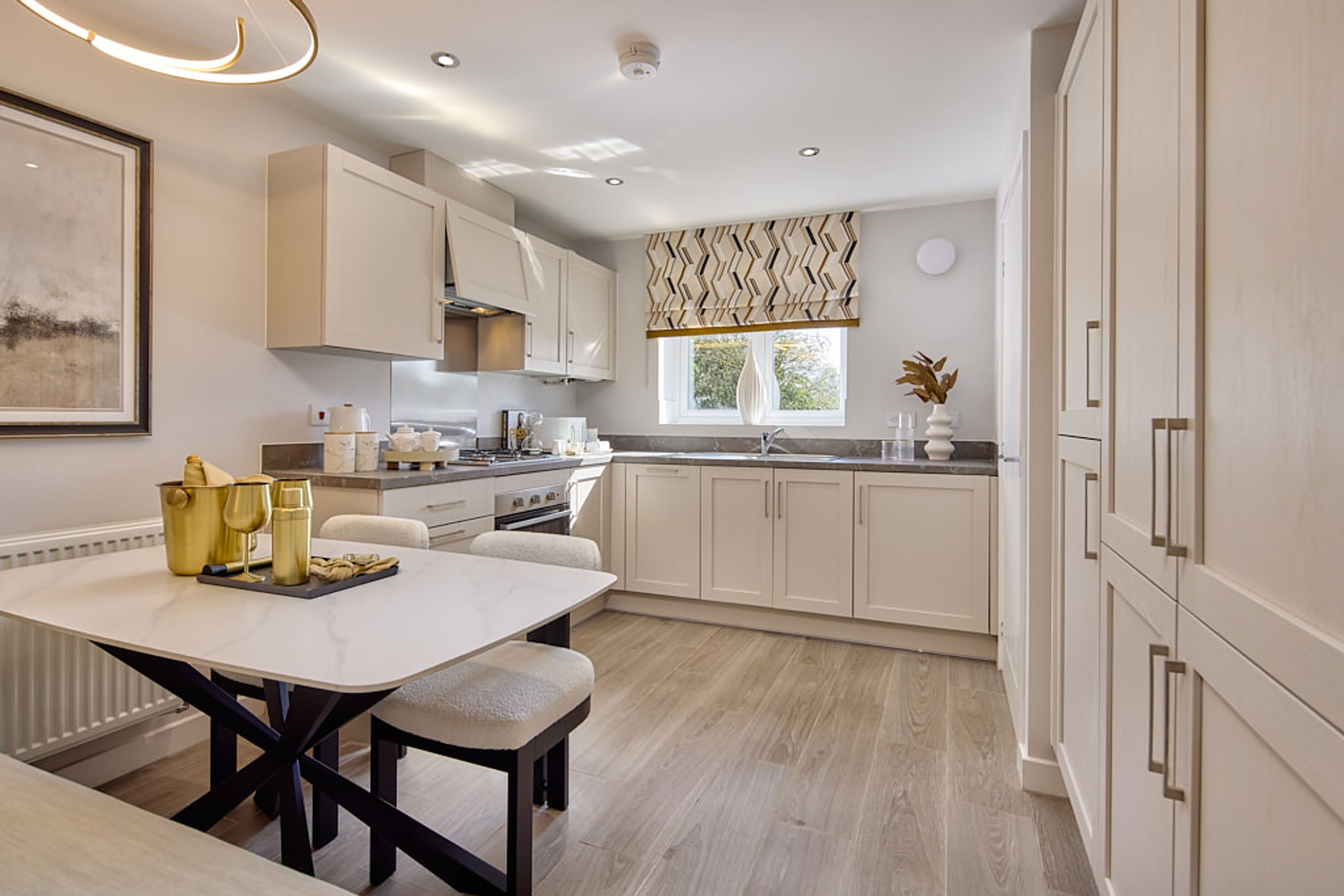 A kitchen and dining area with cream cabinets, a table with chairs, and a window.