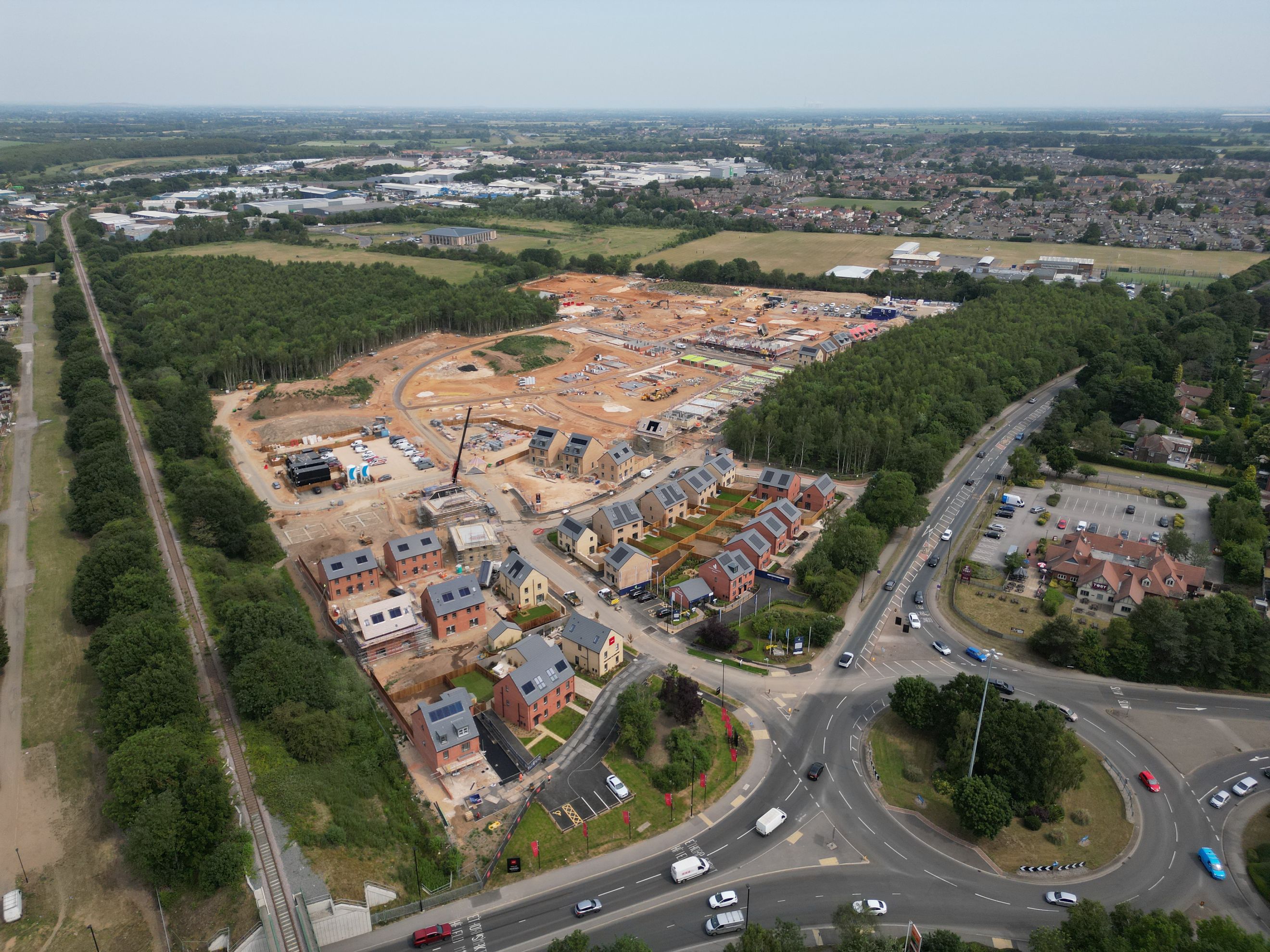 A construction site with new houses being built and a road with cars.