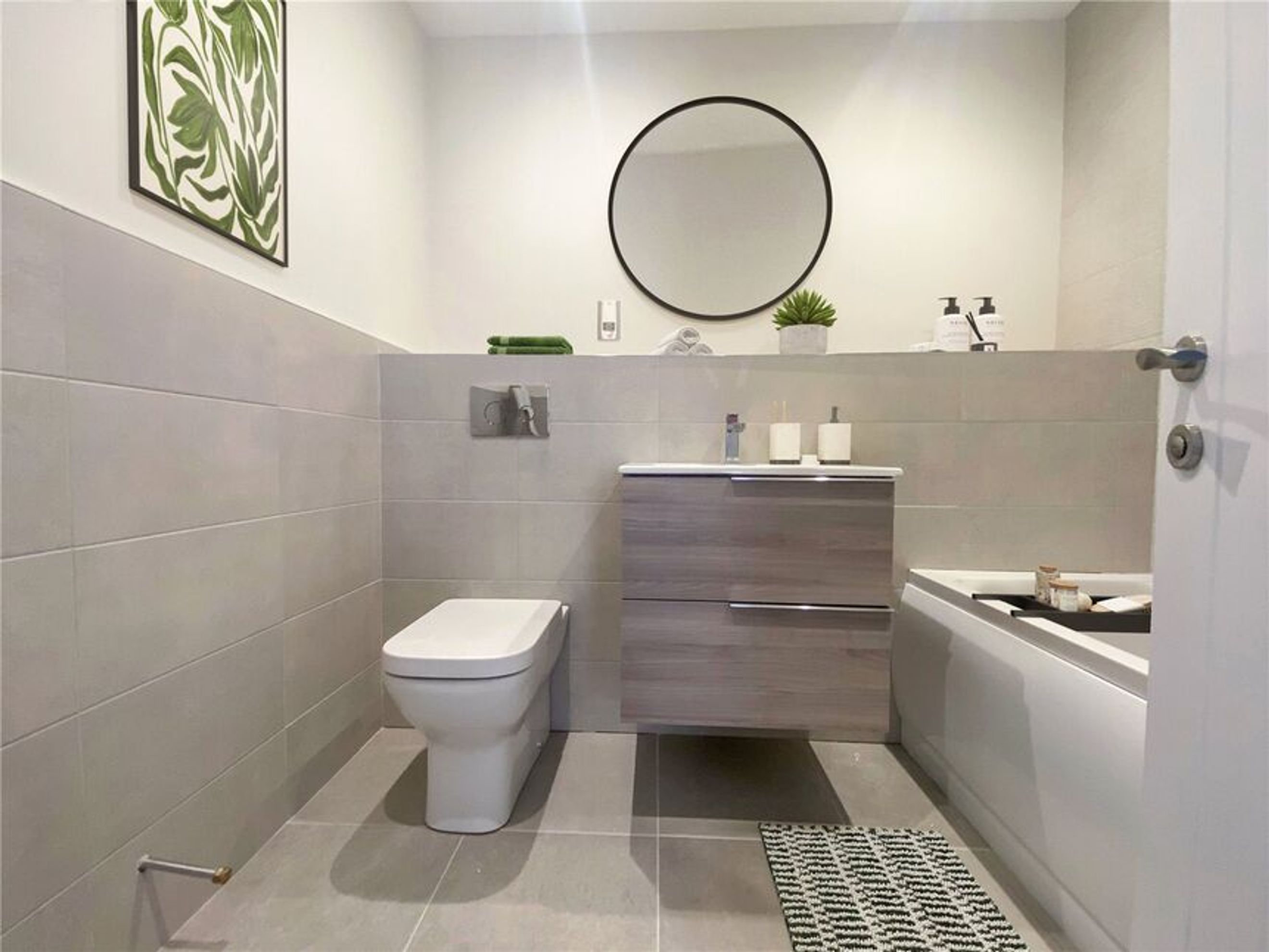 A modern bathroom with a toilet, vanity, and bathtub.