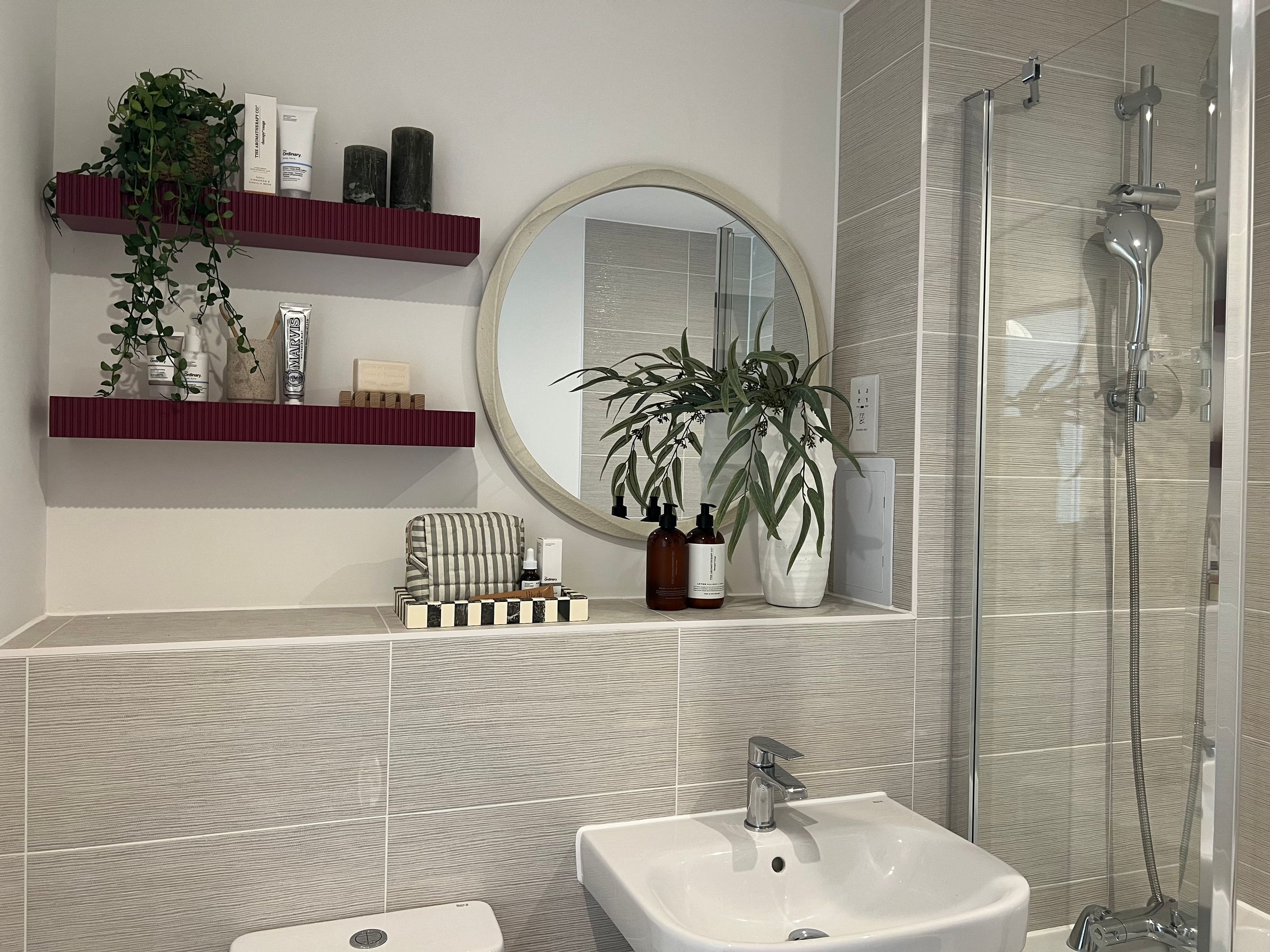 A bathroom vanity with shelves, a mirror, a sink, and a shower.