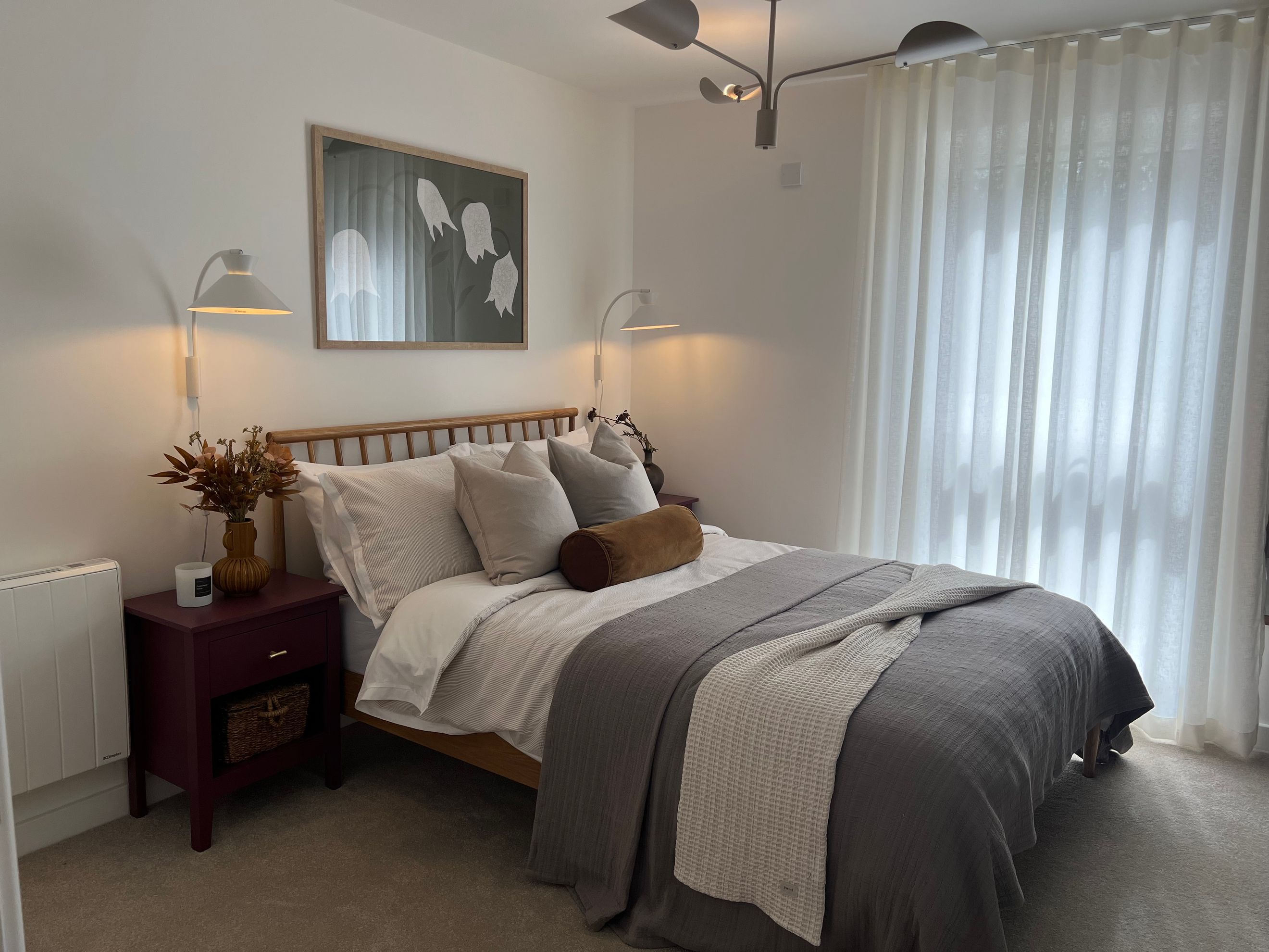 A bedroom with a bed, nightstand, and wall lamps.