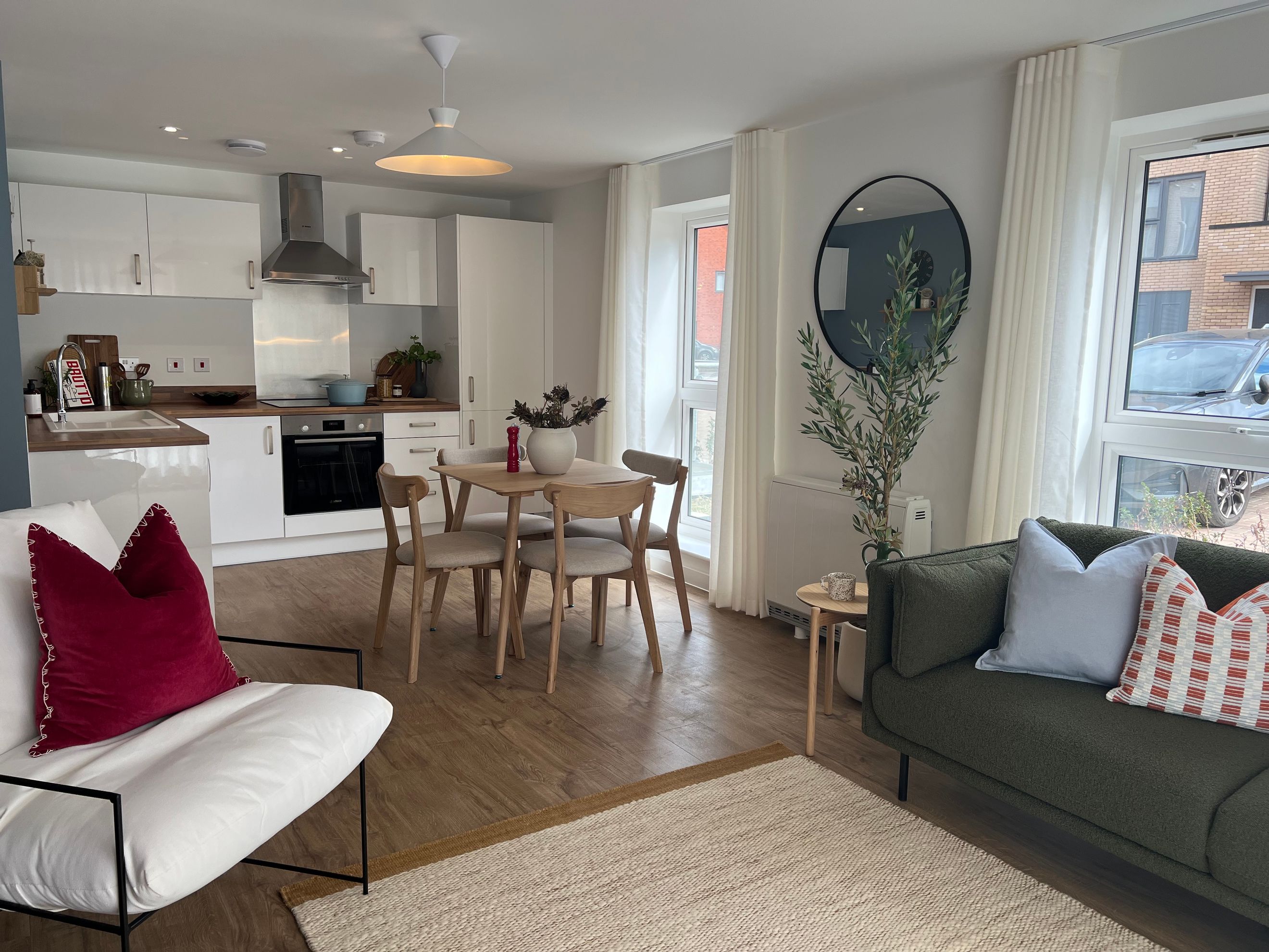 A living room and kitchen area with a dining table, chairs, a sofa, and kitchen cabinets.