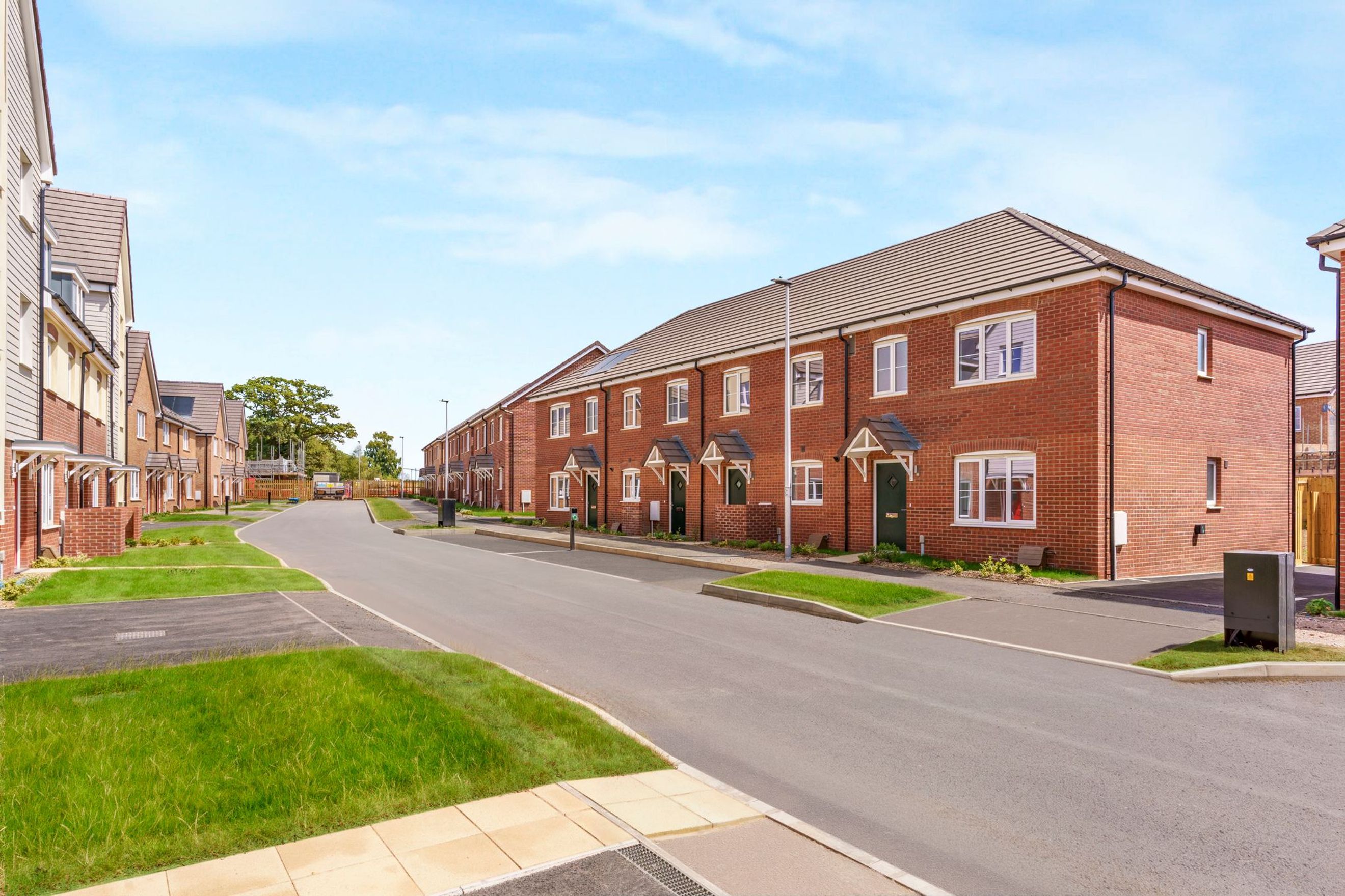 A street lined with red brick townhouses with white windows and green lawns.