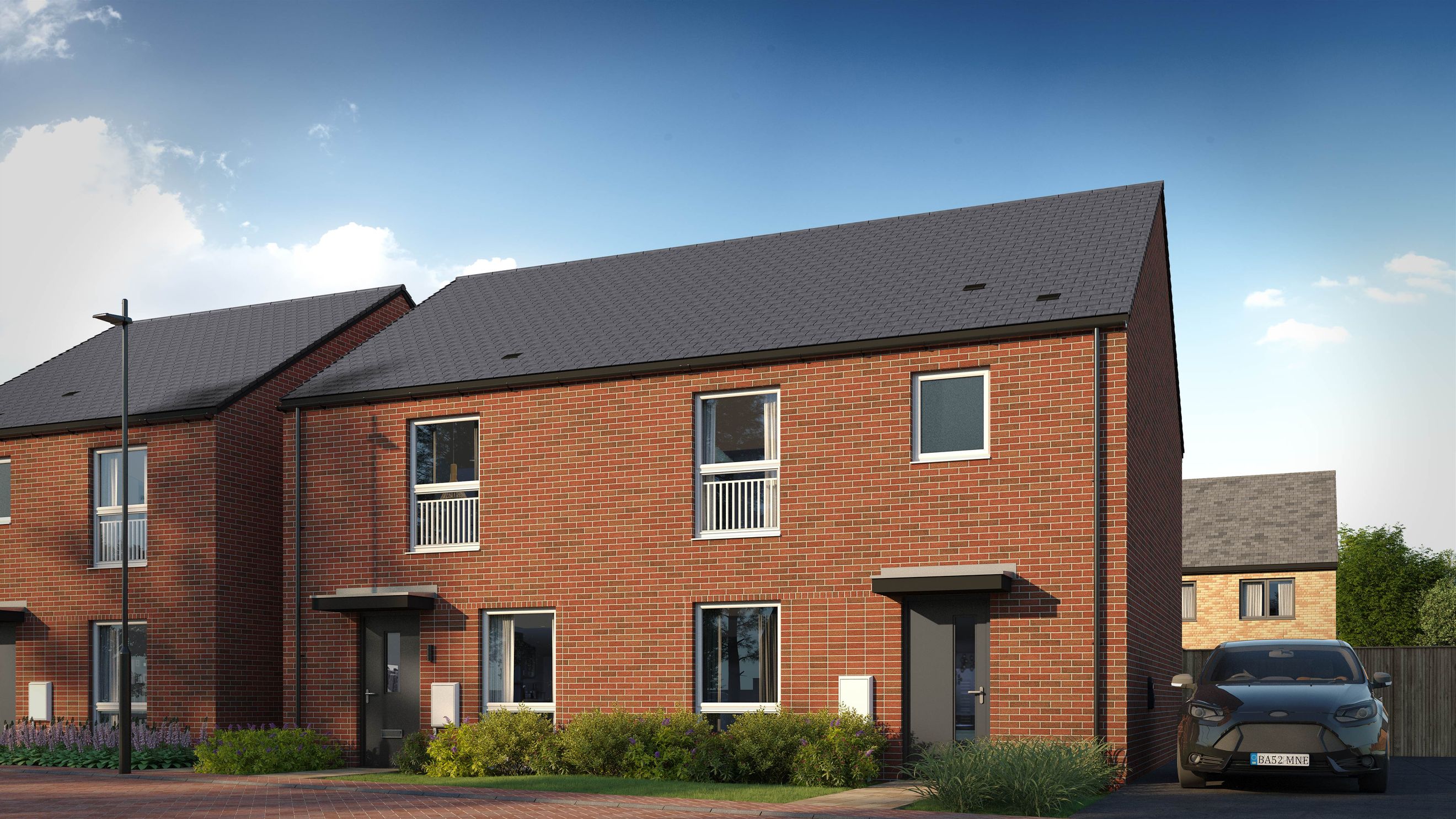 A row of modern brick townhouses with grey roofs under a blue sky with clouds.