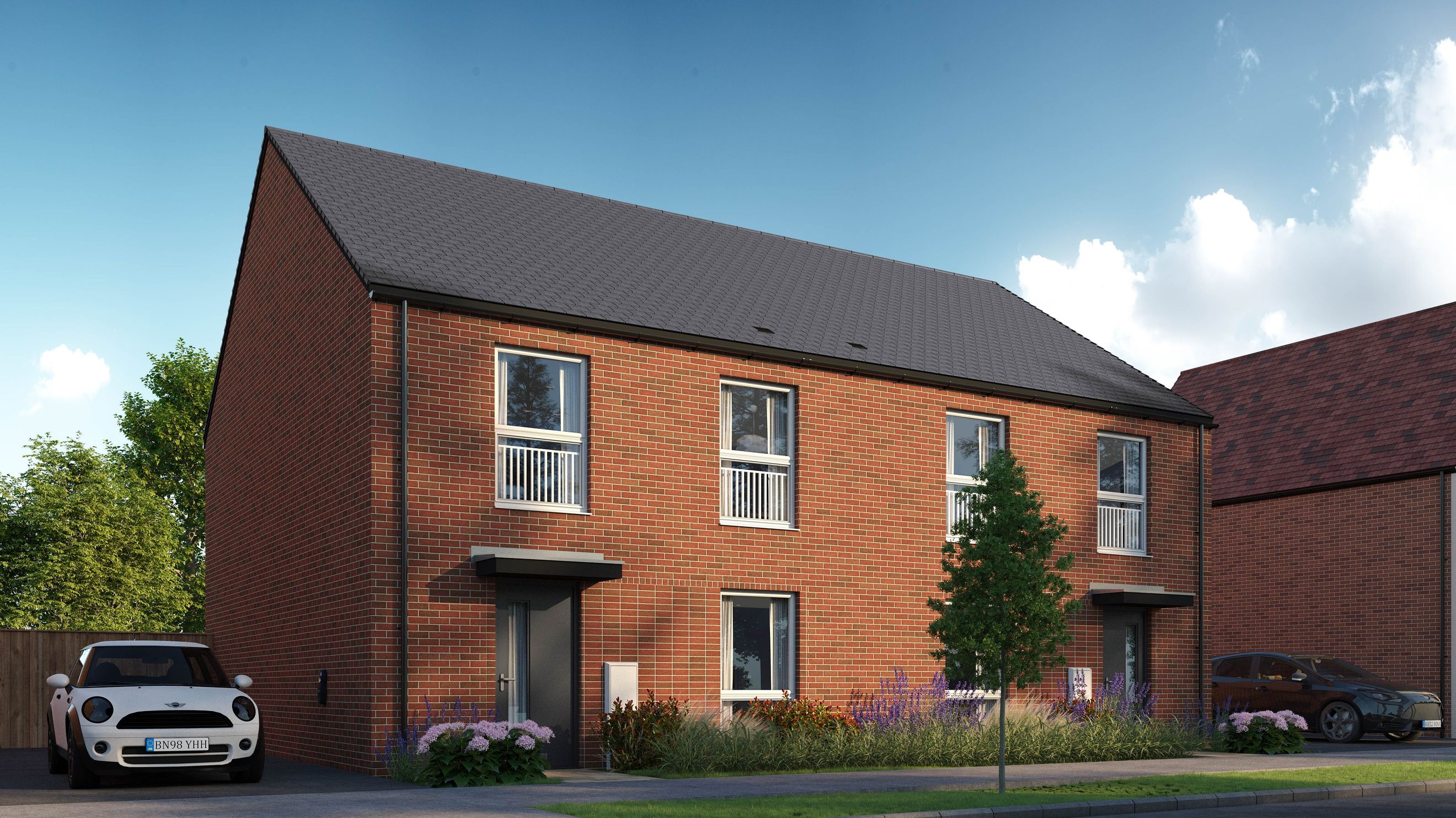 A modern red brick house with a grey roof, featuring multiple windows and a dark grey front door.