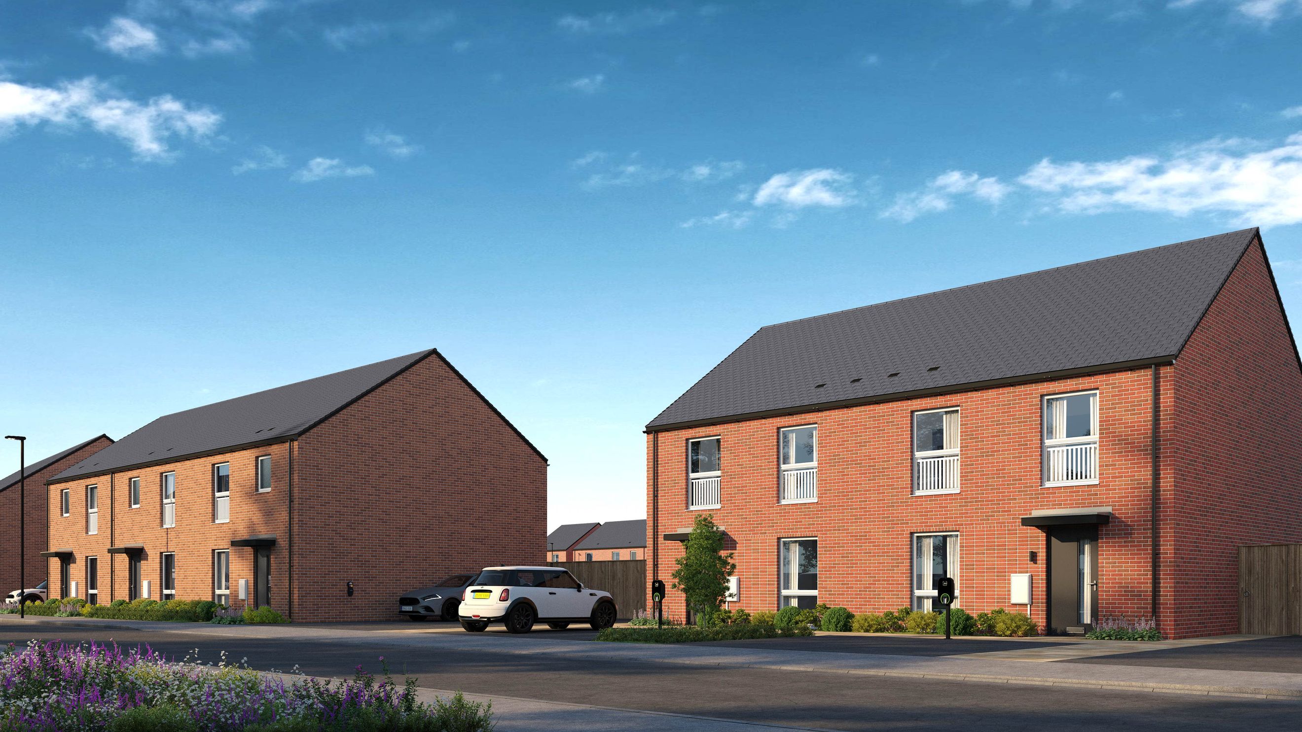 A street view of modern brick townhouses with cars parked in front.