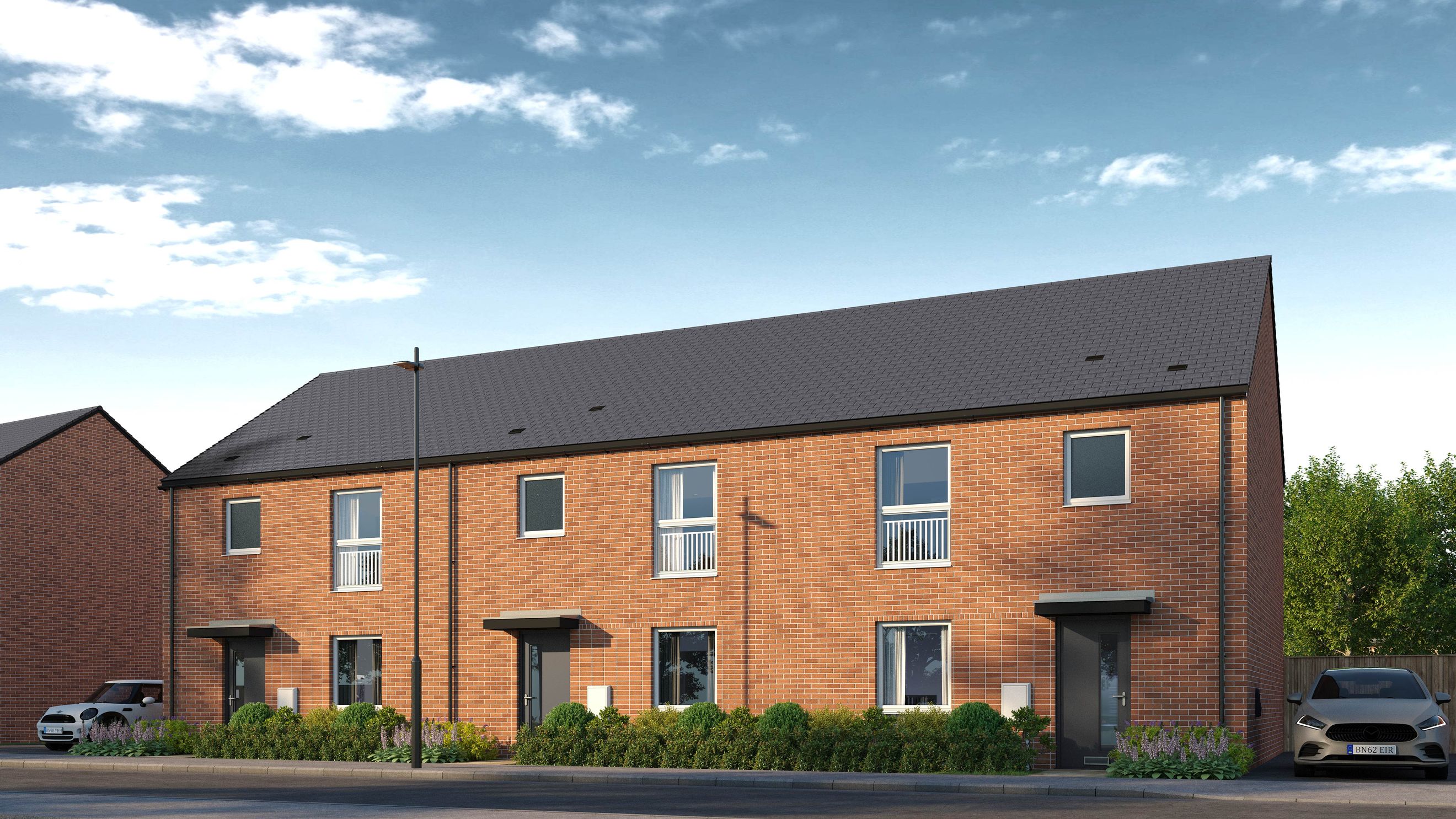 A row of modern brick townhouses with dark roofs and manicured front gardens.
