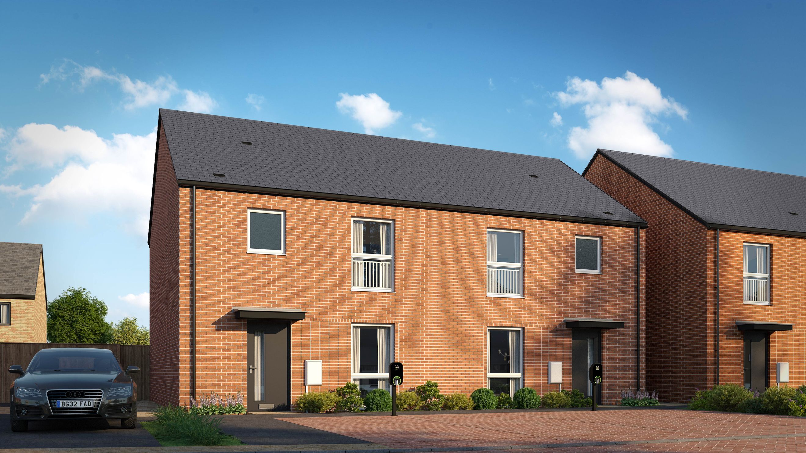 A row of modern brick townhouses with dark grey doors and electric vehicle charging stations.