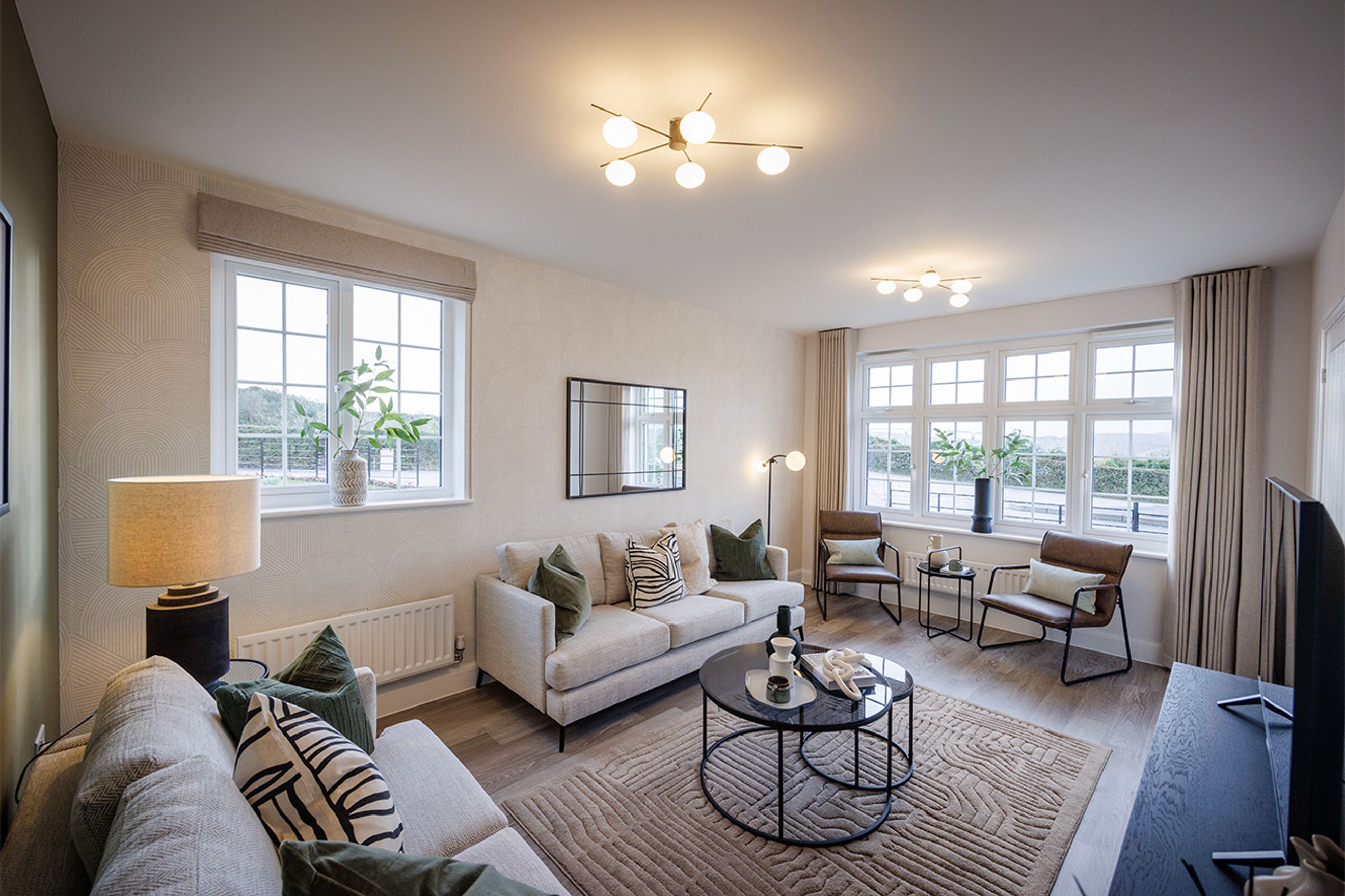 A living room with a sofa, chairs, coffee table, and windows.