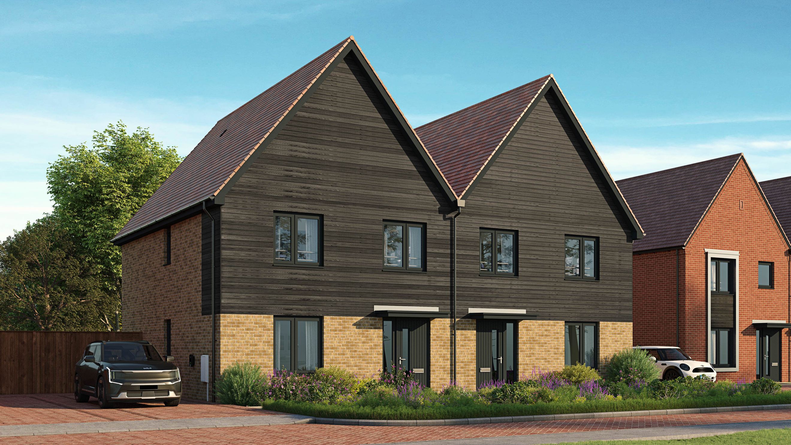 A modern house with dark wood siding and brick lower walls, featuring multiple windows and a pitched roof.