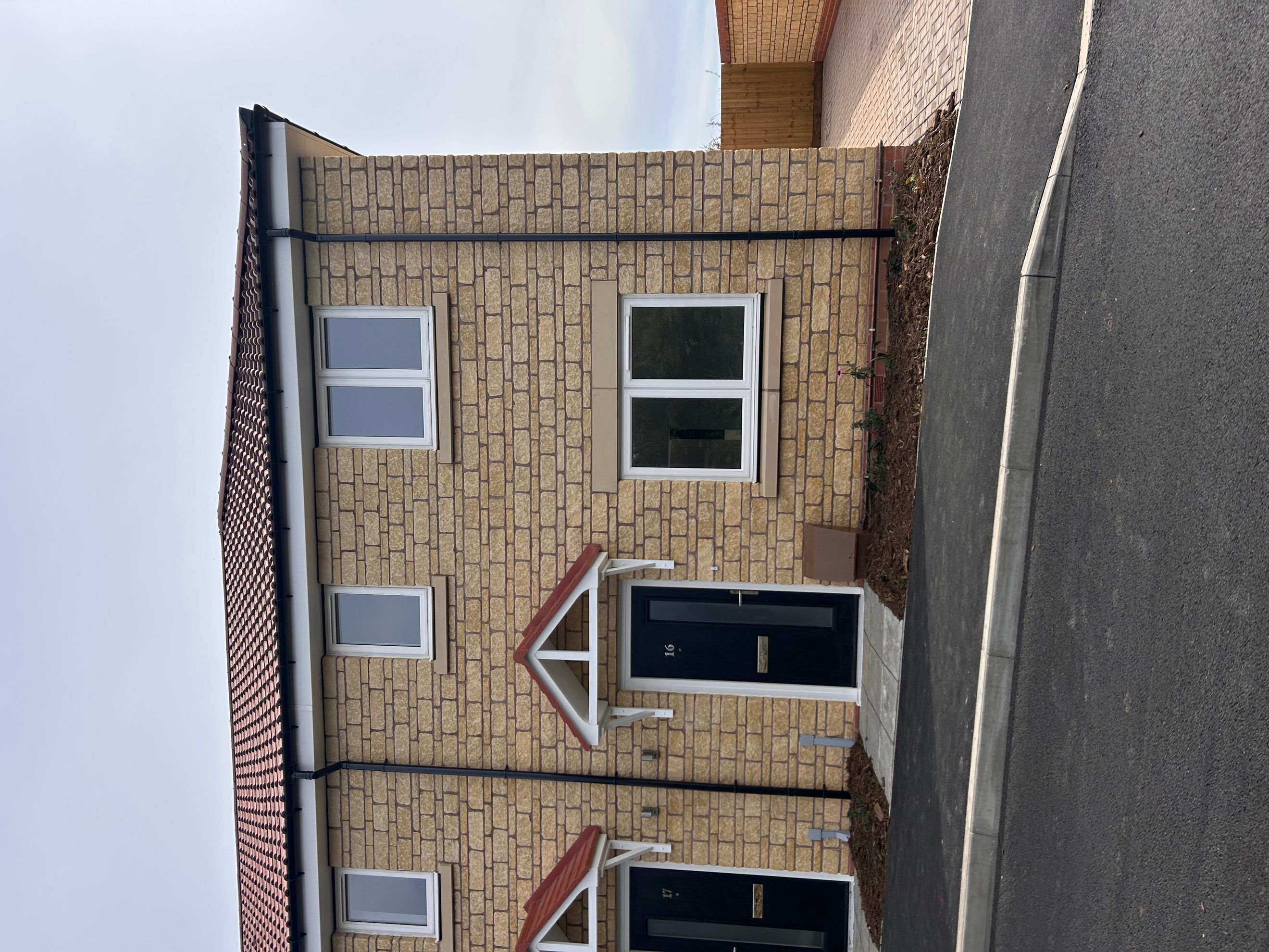 A modern house with stone-effect brickwork and black front doors.