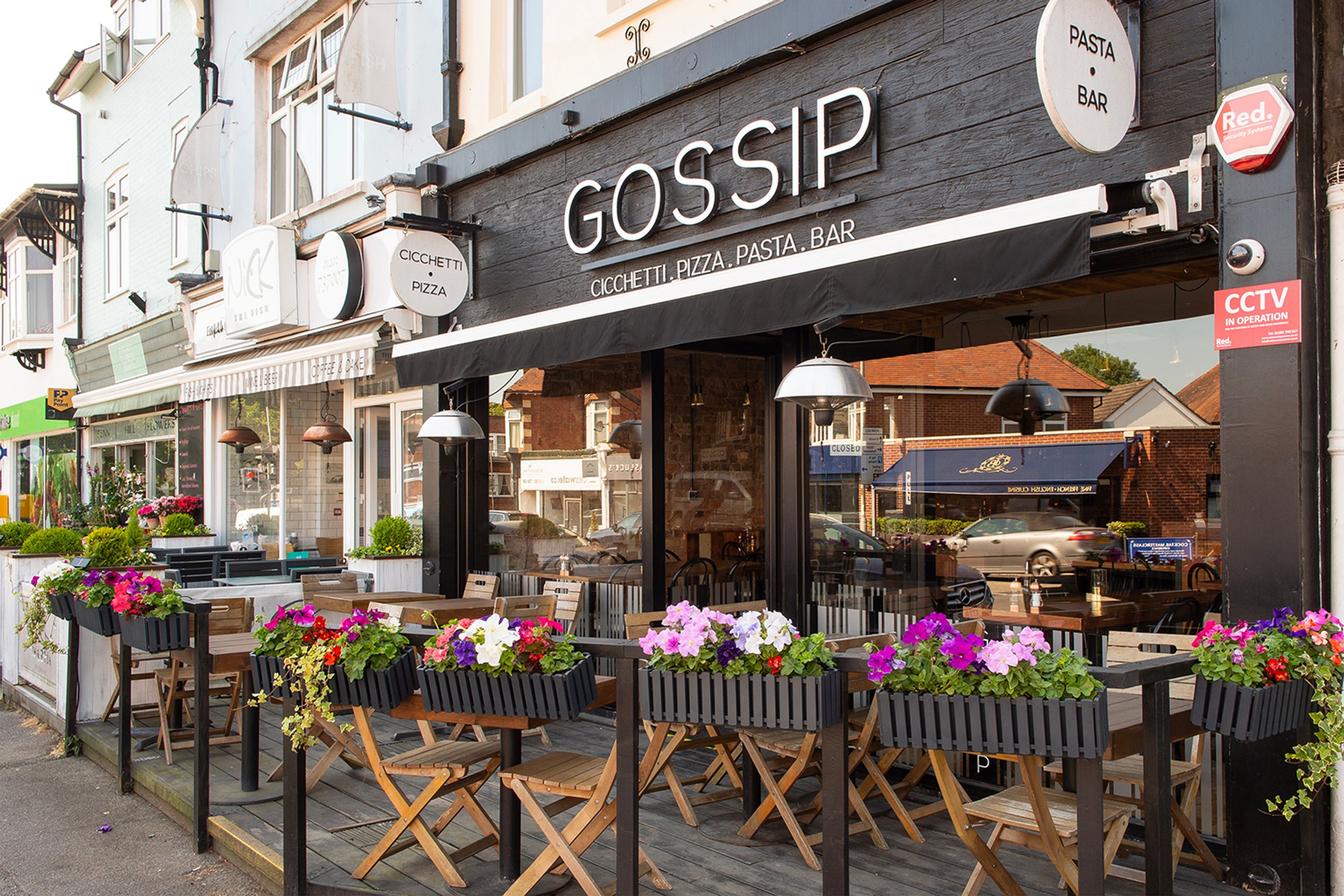 A restaurant with outdoor seating and flower boxes.