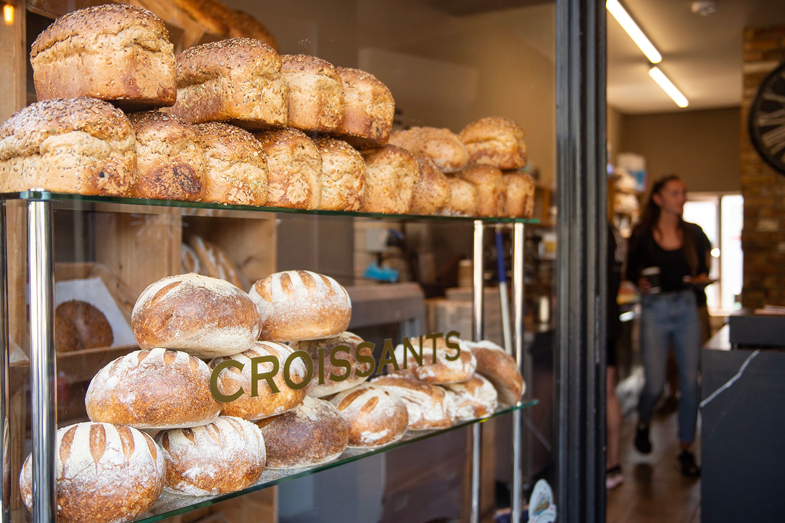 A display of various loaves of bread and croissants in a bakery window.