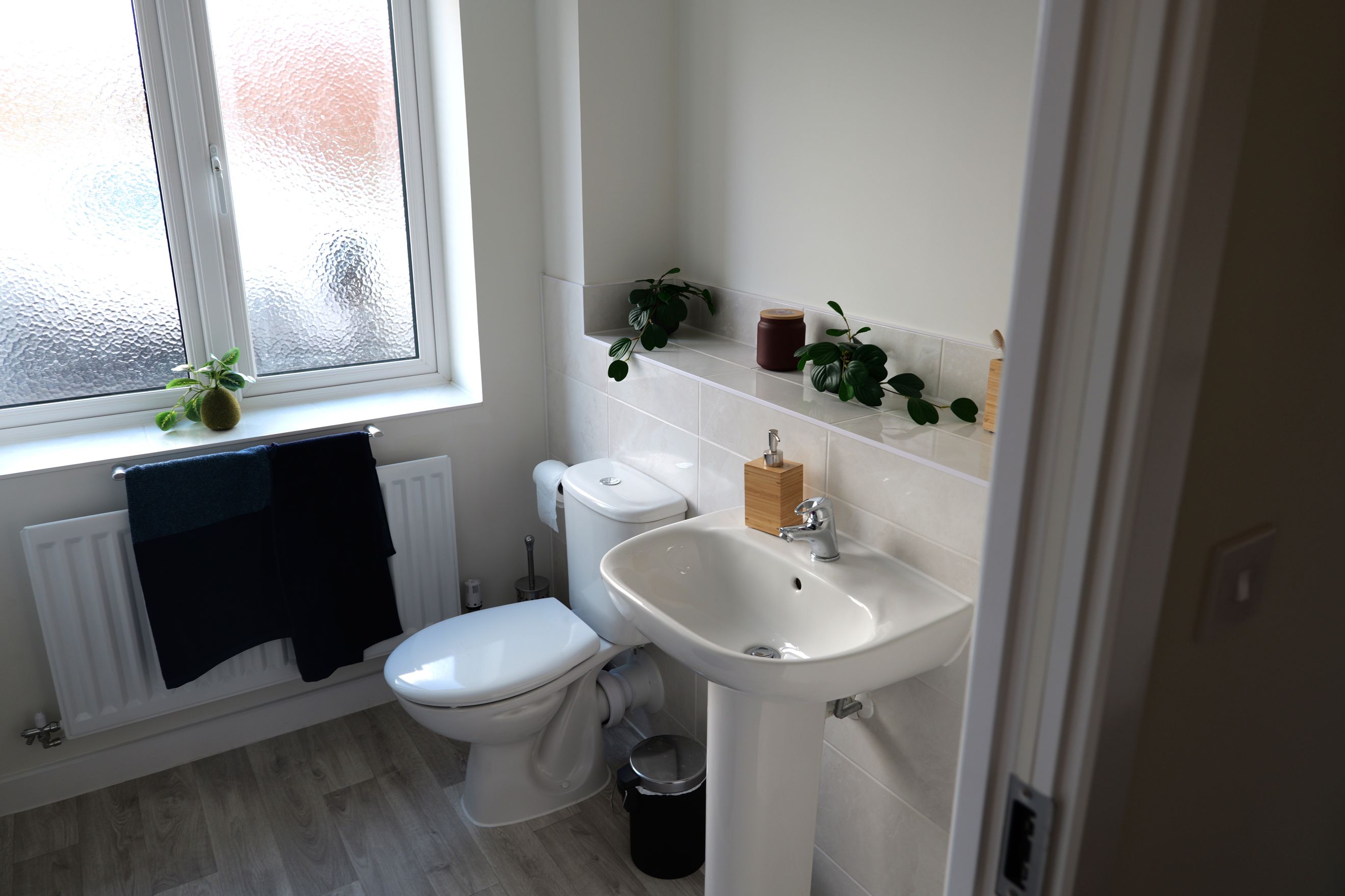 A bathroom with a toilet, sink, and a window.