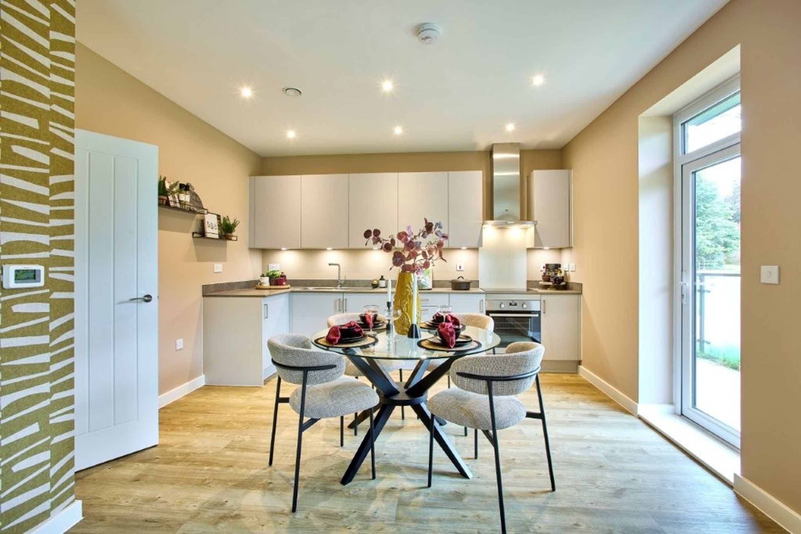 A dining area and kitchen with a glass-top table, chairs, and modern cabinetry.