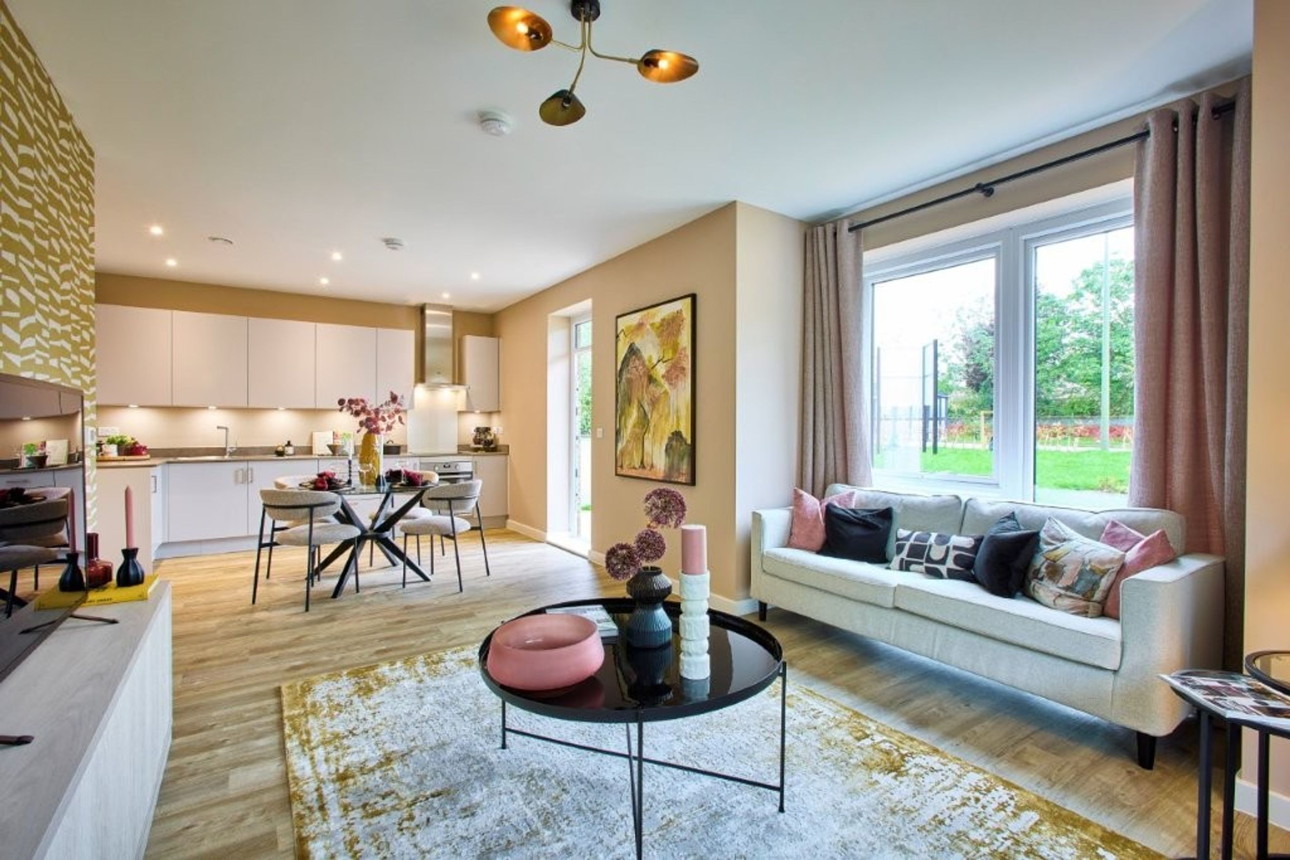 A living room and kitchen area with a sofa, coffee table, dining table, and kitchen cabinets.