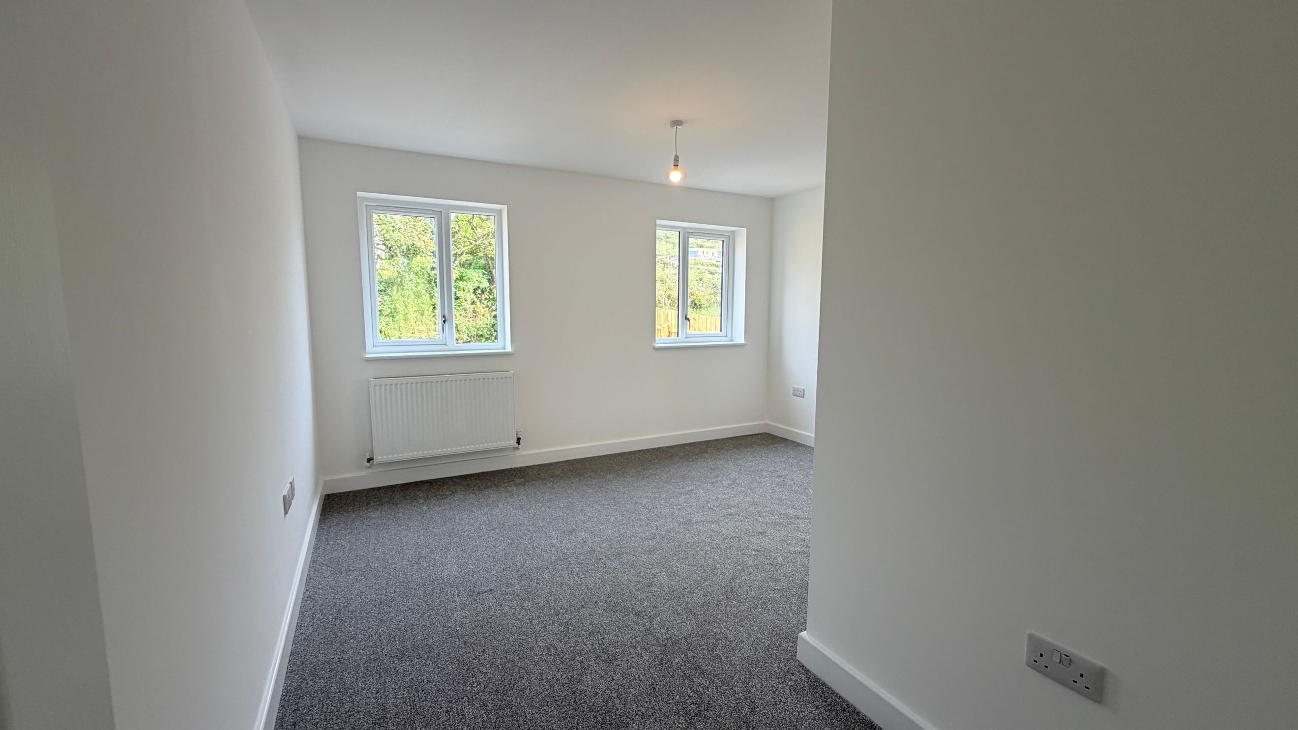 A bedroom with two windows and a radiator.