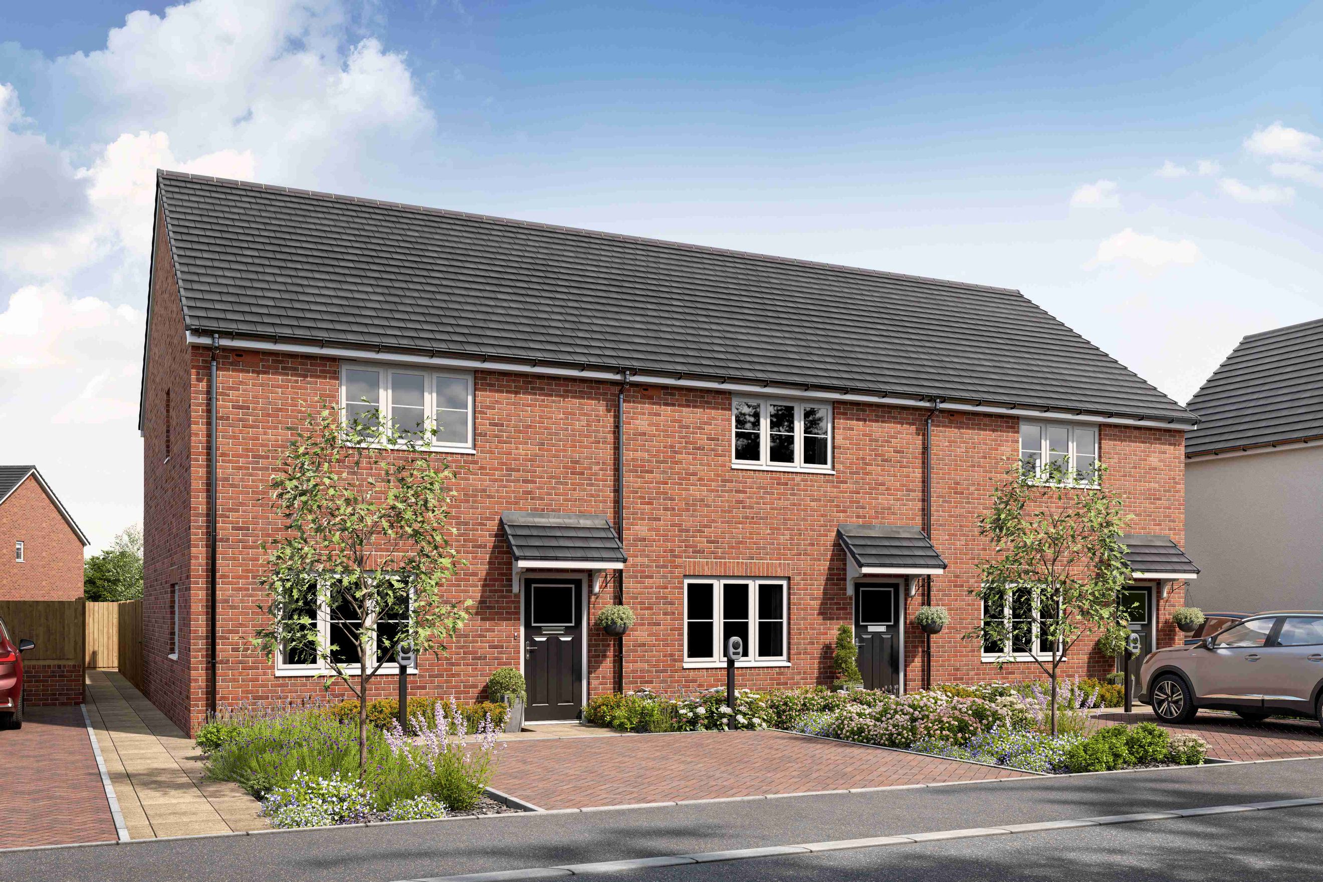 A row of red brick houses with grey tiled roofs and manicured front gardens.