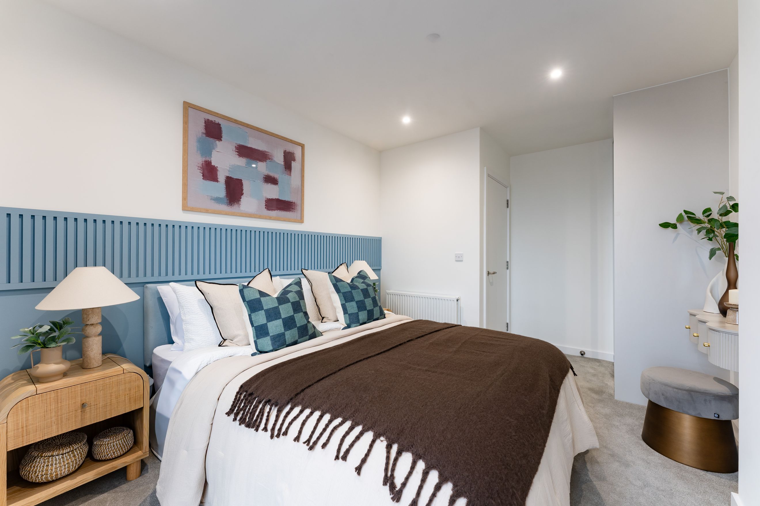A bedroom with a bed, nightstand, and artwork.